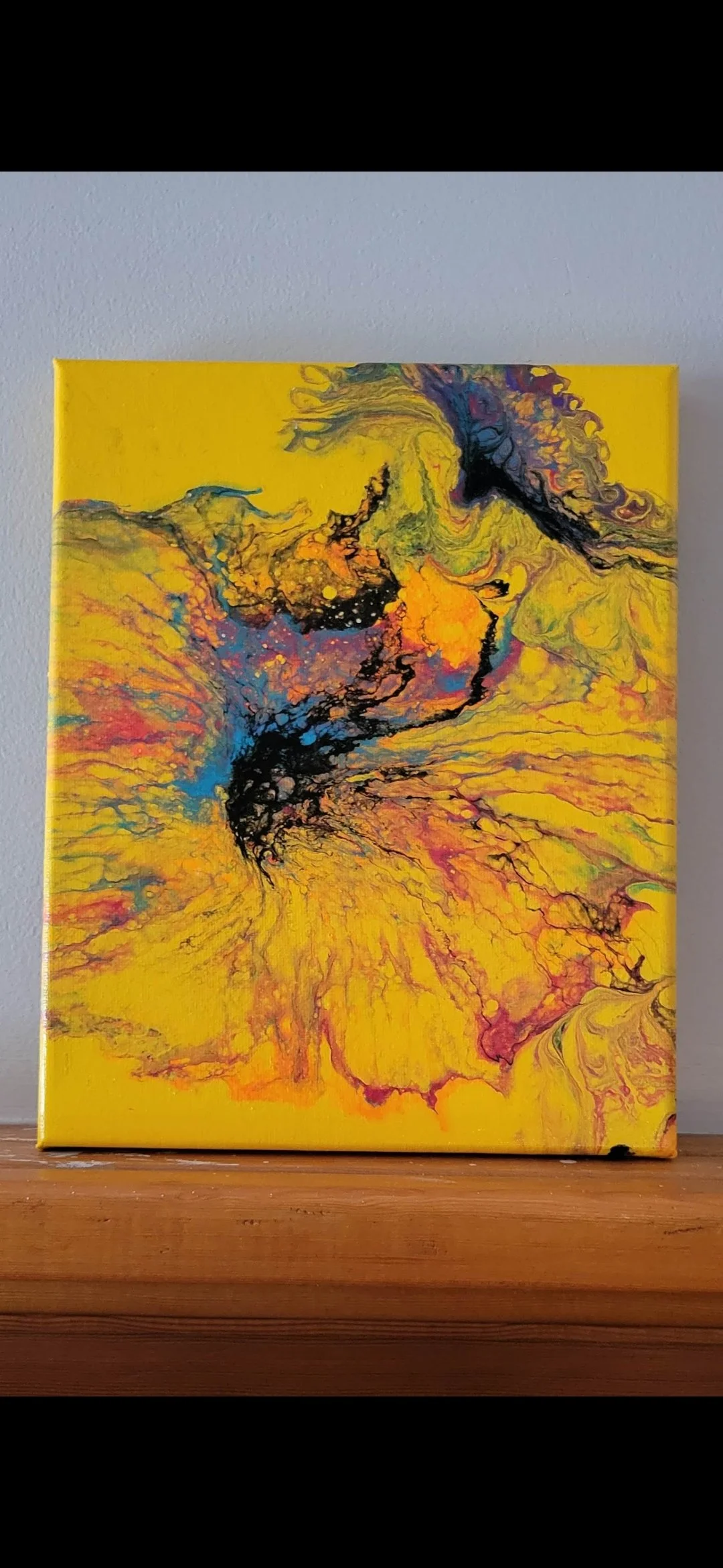 Abstract yellow, black, orange, blue, and purple swirling painting on canvas.