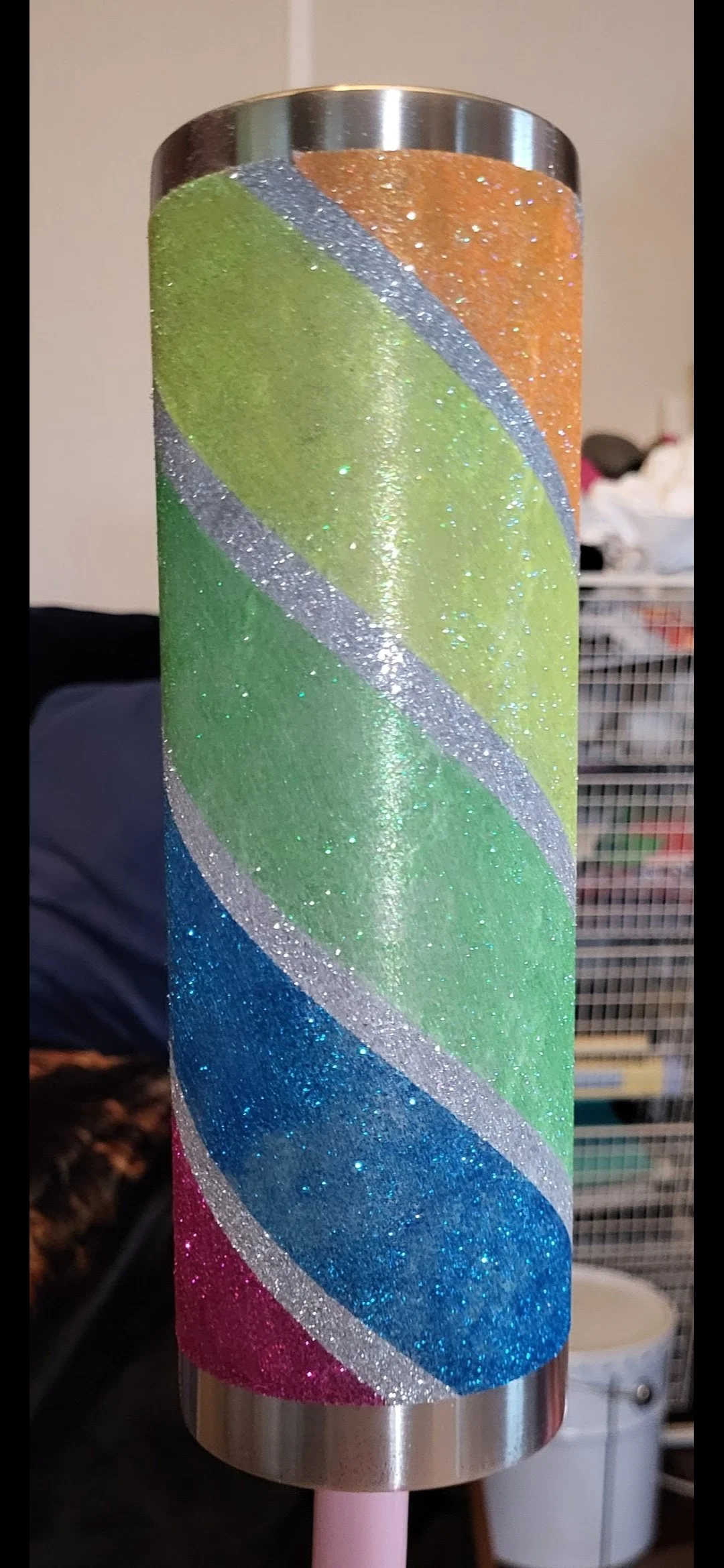 Colorful glittery cylindrical object with rainbow stripes in orange, yellow, green, blue, and pink.