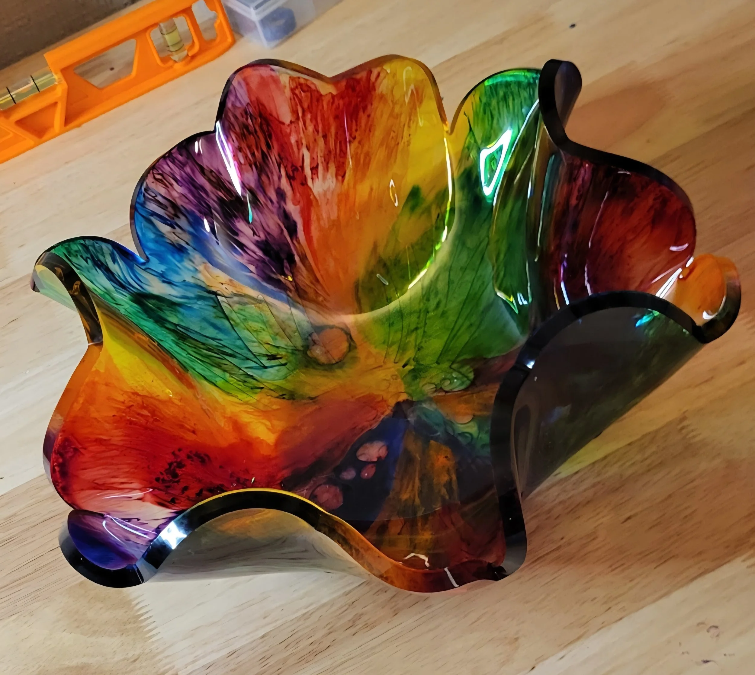 Colorful glass bowl with a flower shape, placed on a wooden table.