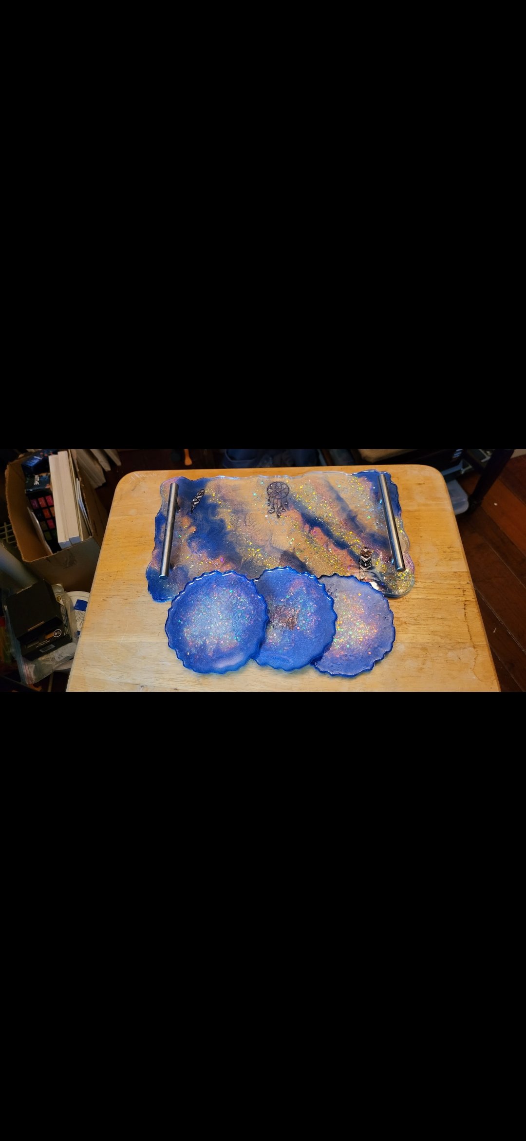 Set of handmade resin coasters with iridescent glitter on a wooden table.