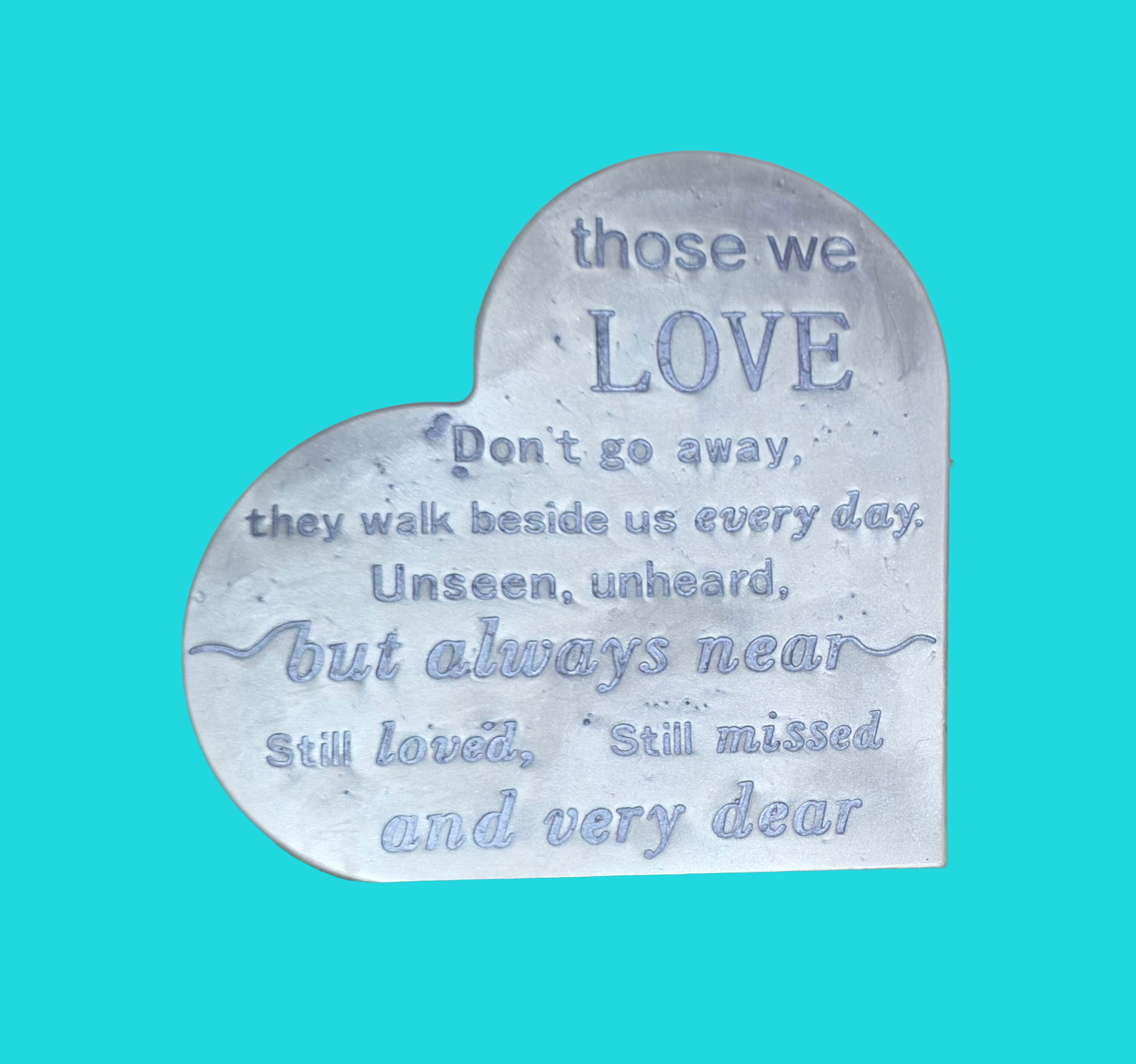 A heart-shaped engraved plaque with a sentimental message about love, against a bright blue background.