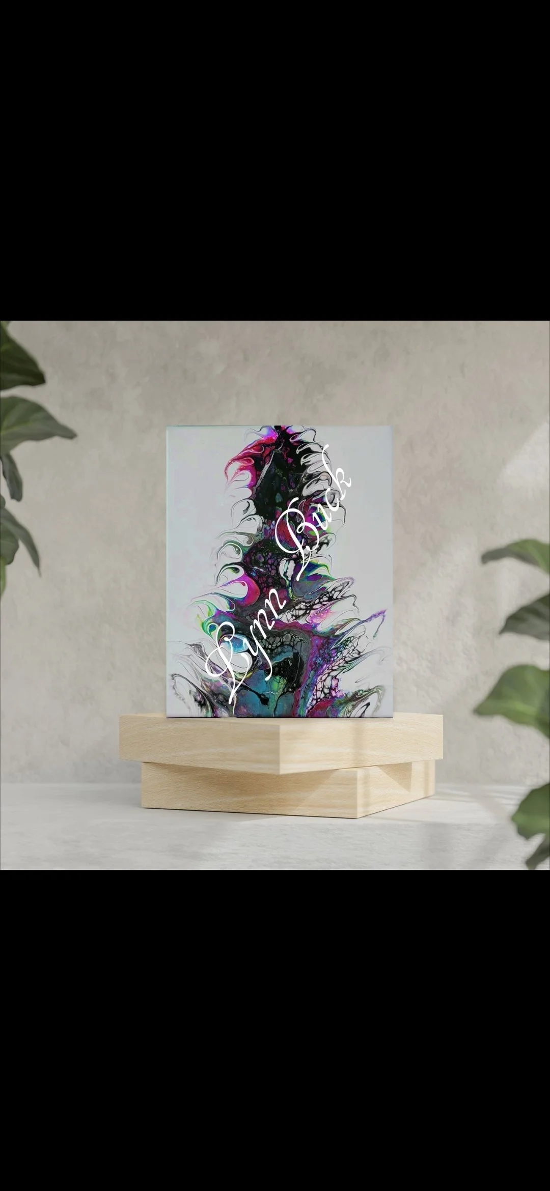 A colorful abstract art print on a white canvas, with swirling patterns in black, pink, purple, blue, and green, resting on a light wooden stand.