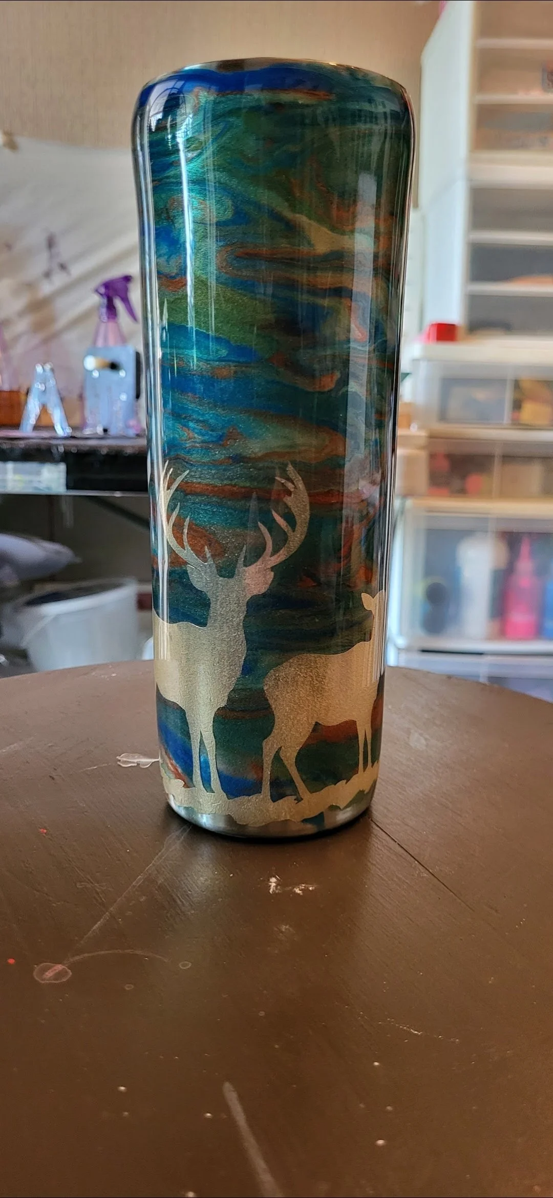 A cylindrical tumbler with a scenic woodland design featuring two deer, set against a colorful abstract background resembling a sky with clouds.