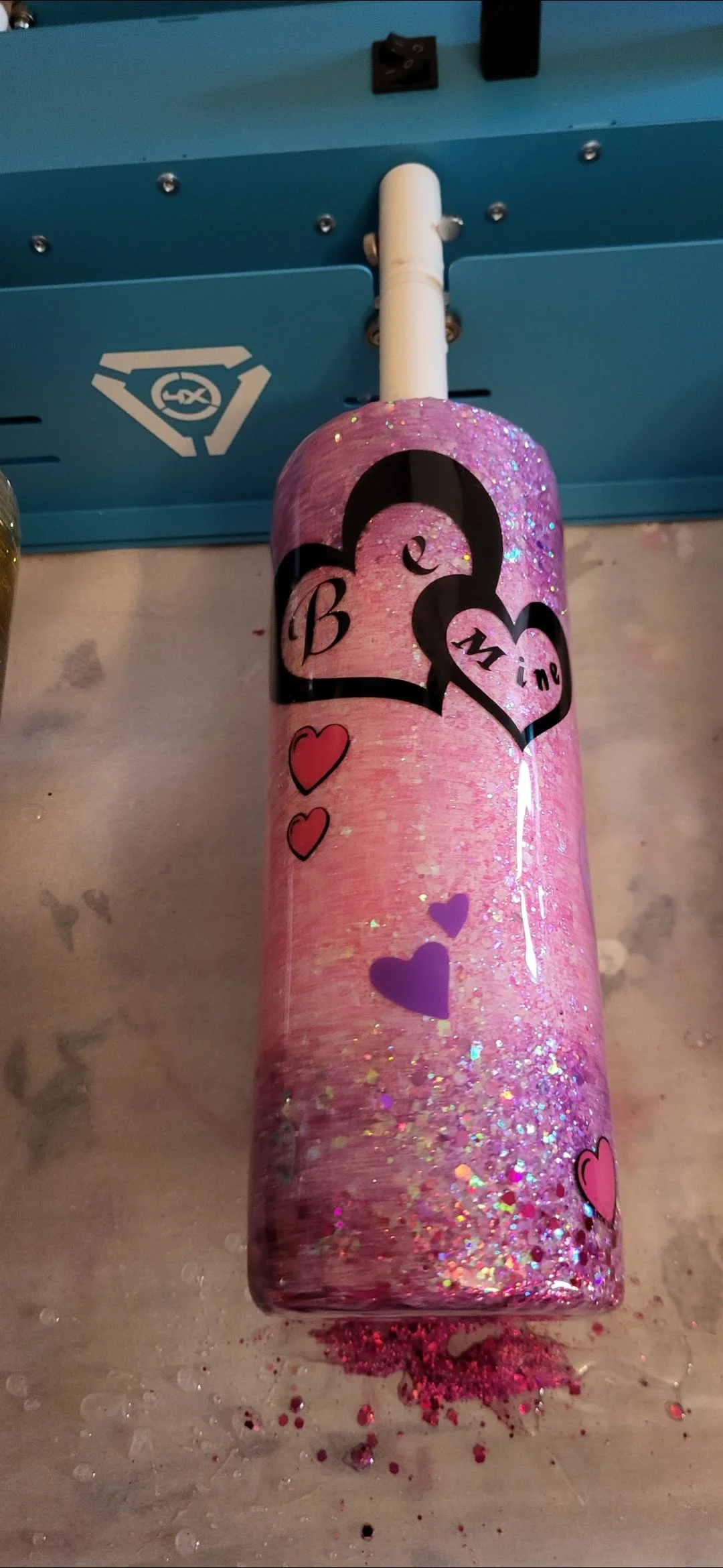 Pink glitter bottle decorated with hearts and the words "Be Mine" in a heart shape.