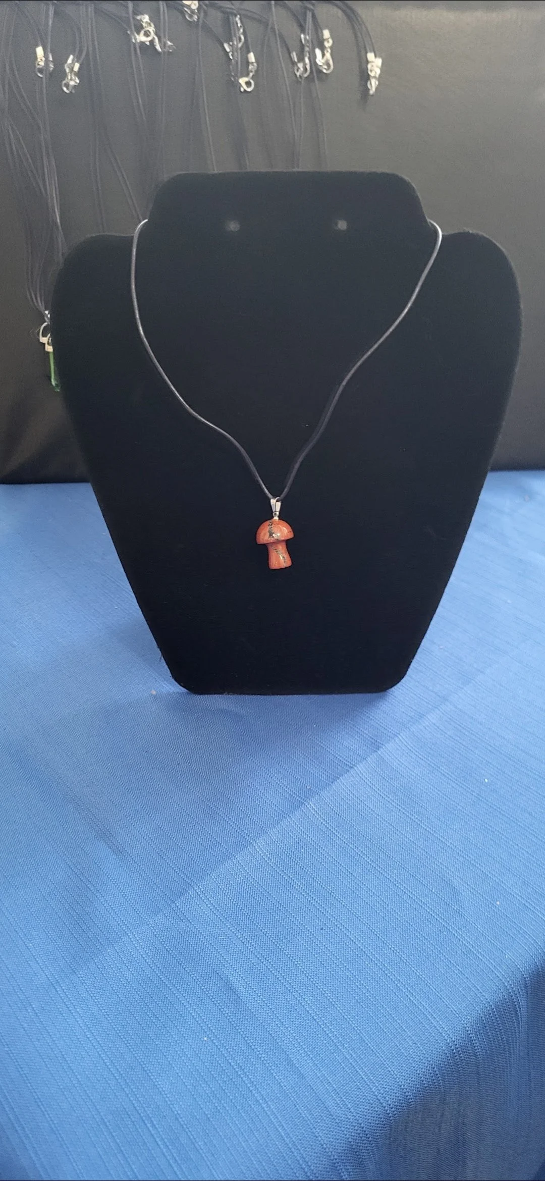 Necklace with a mushroom-shaped pendant displayed on a black jewelry stand.