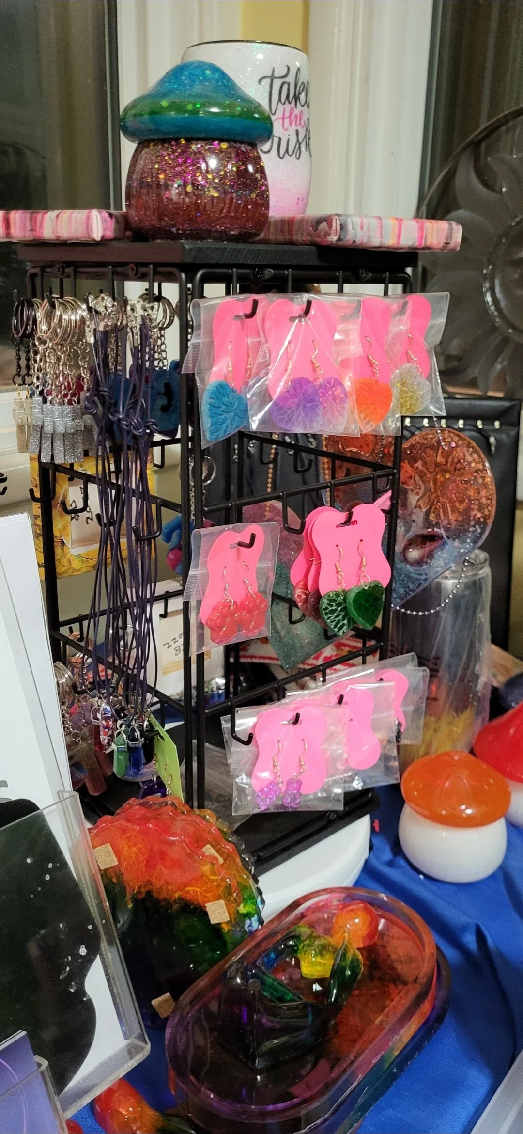 Display of colorful glass jewelry and decorative items on a table, including earrings and ornaments.