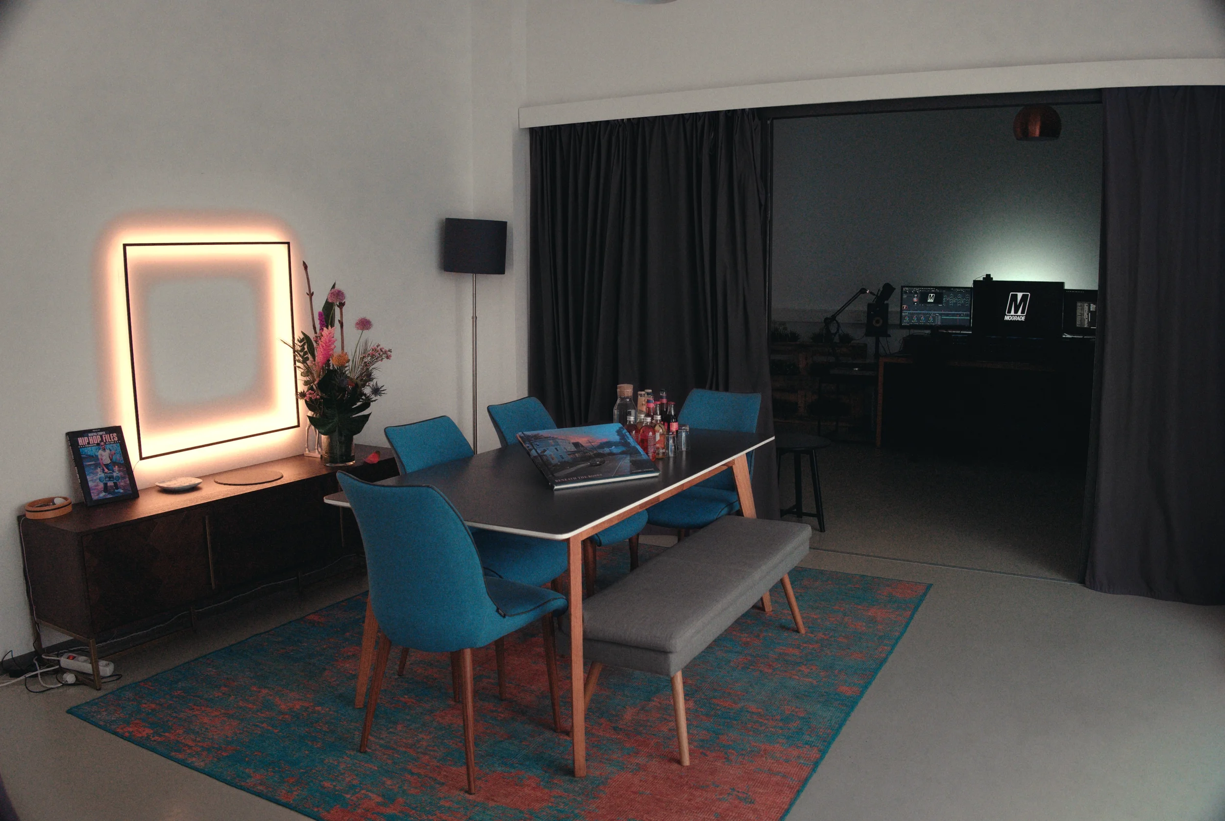 Suite 1 or 2 of MOGRADE's post-production studio, divided into two spaces – a casual meeting space at the front and a post-production workstation at the back, divided by black curtains.