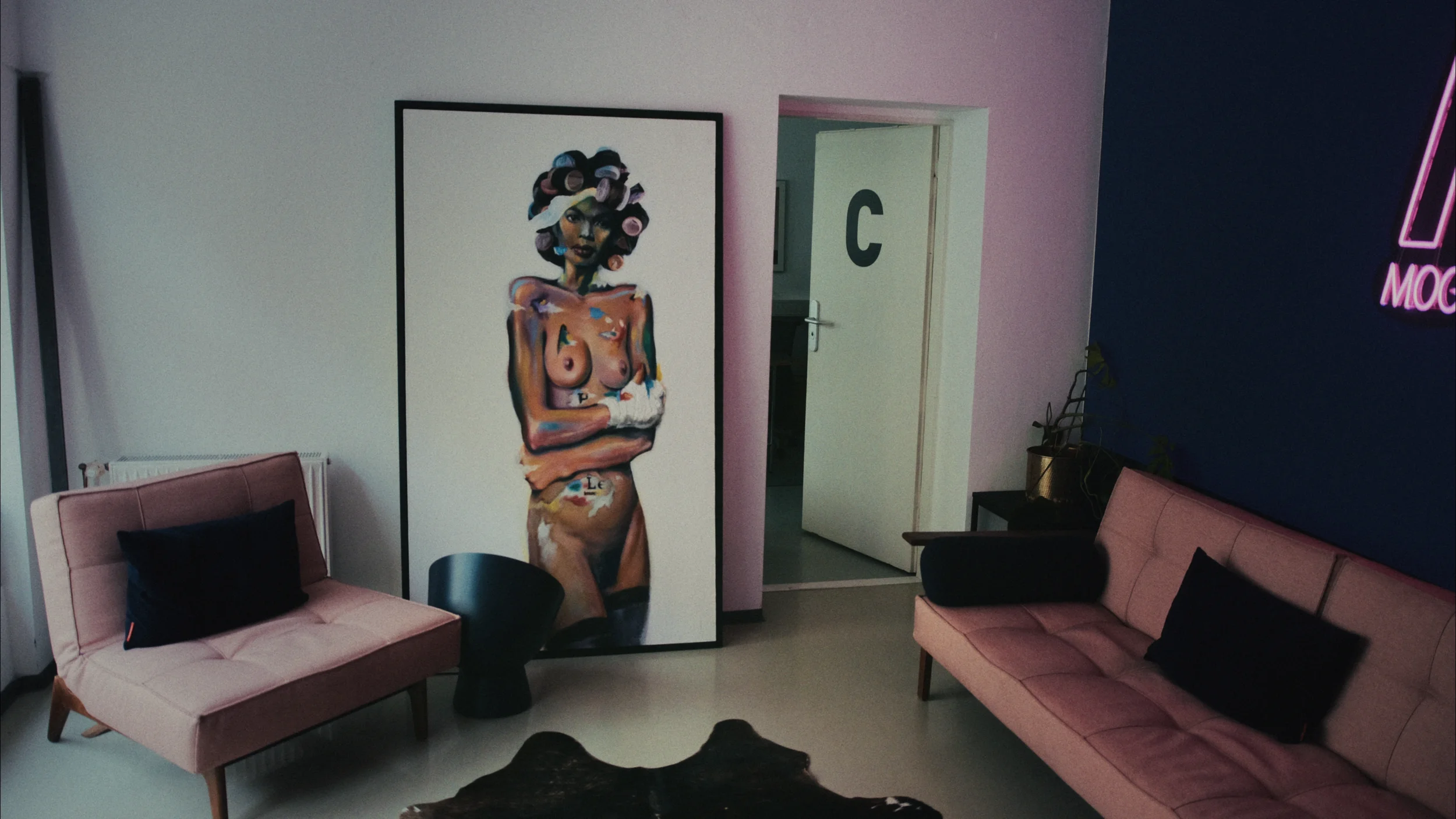 View of MOGRADE's studio interior, decorated with velvety sofas, black cushions, plants and a large framed artwork.