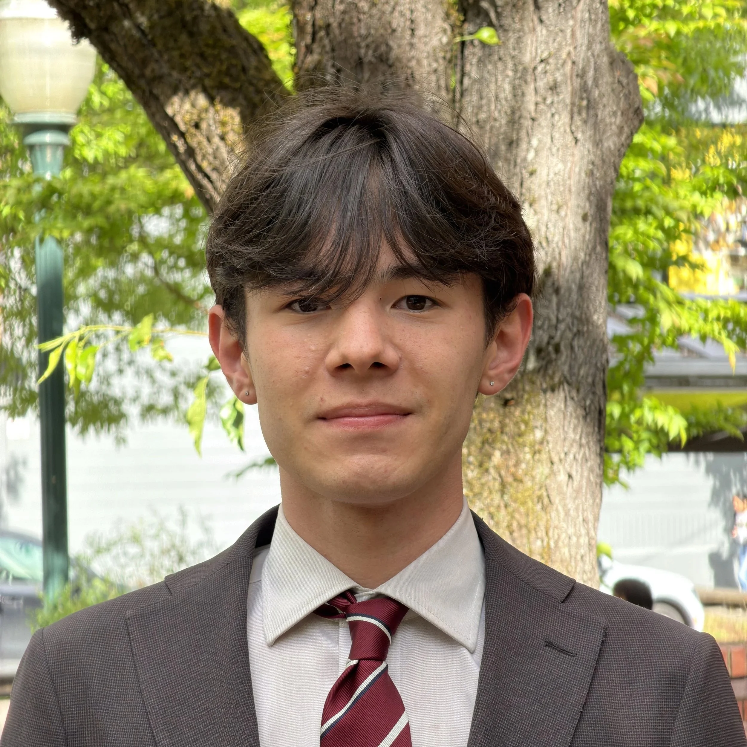 Young man in a suit and tie smiling in a professional setting.