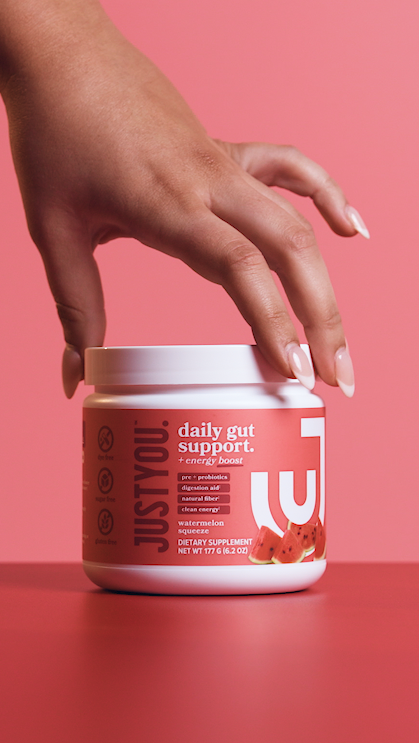 Hand reaching for a white jar labeled 'Just You', with watermelon images on a pink background.