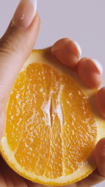 Person holding a halved orange with visible juicy pulp.