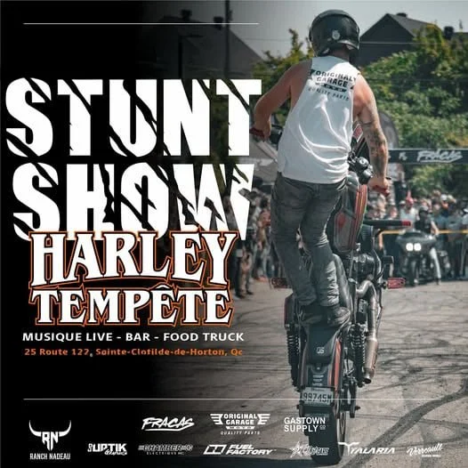 Un motocycliste effectuant une figure à vélo lors d'un événement appelé 'Stunt Show Harley Tempête' avec foule en arrière-plan, affichant des détails de l'événement à Sainte-Clotilde-de-Horton, Québec.