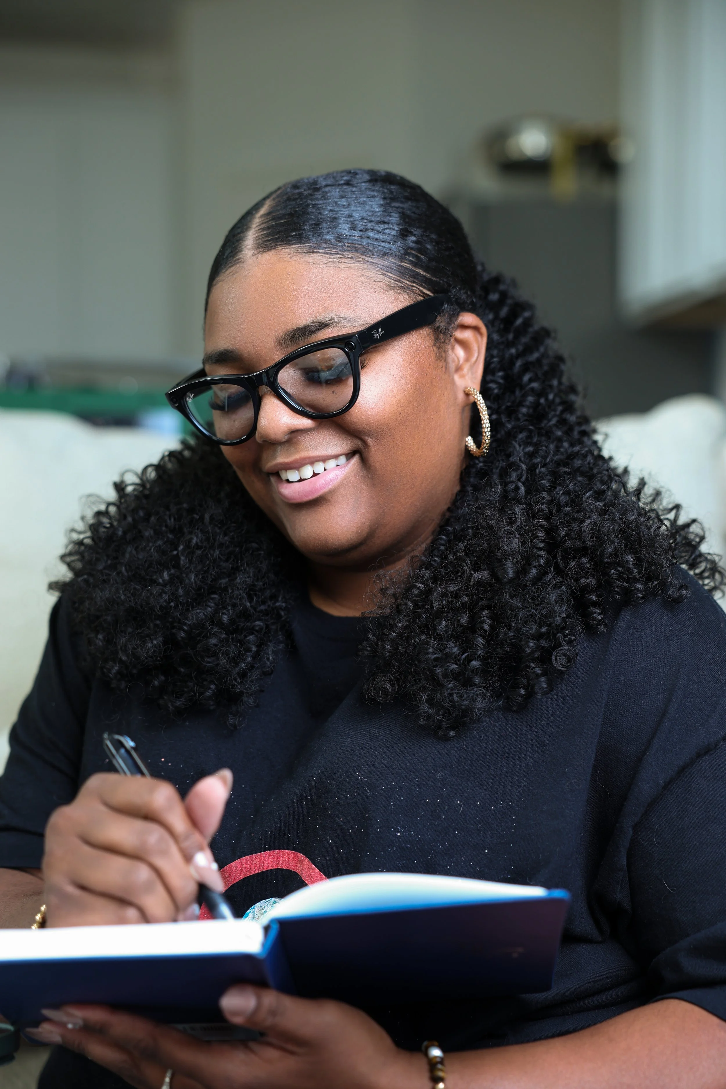 A beige ceramic vase with a single dried flower inside, placed on a wooden surface with sunlight casting shadows.