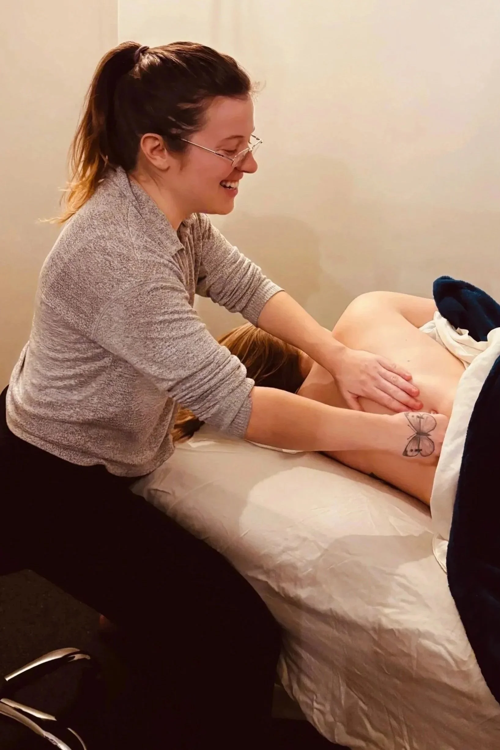 A woman receiving a massage from a therapist in a massage room.