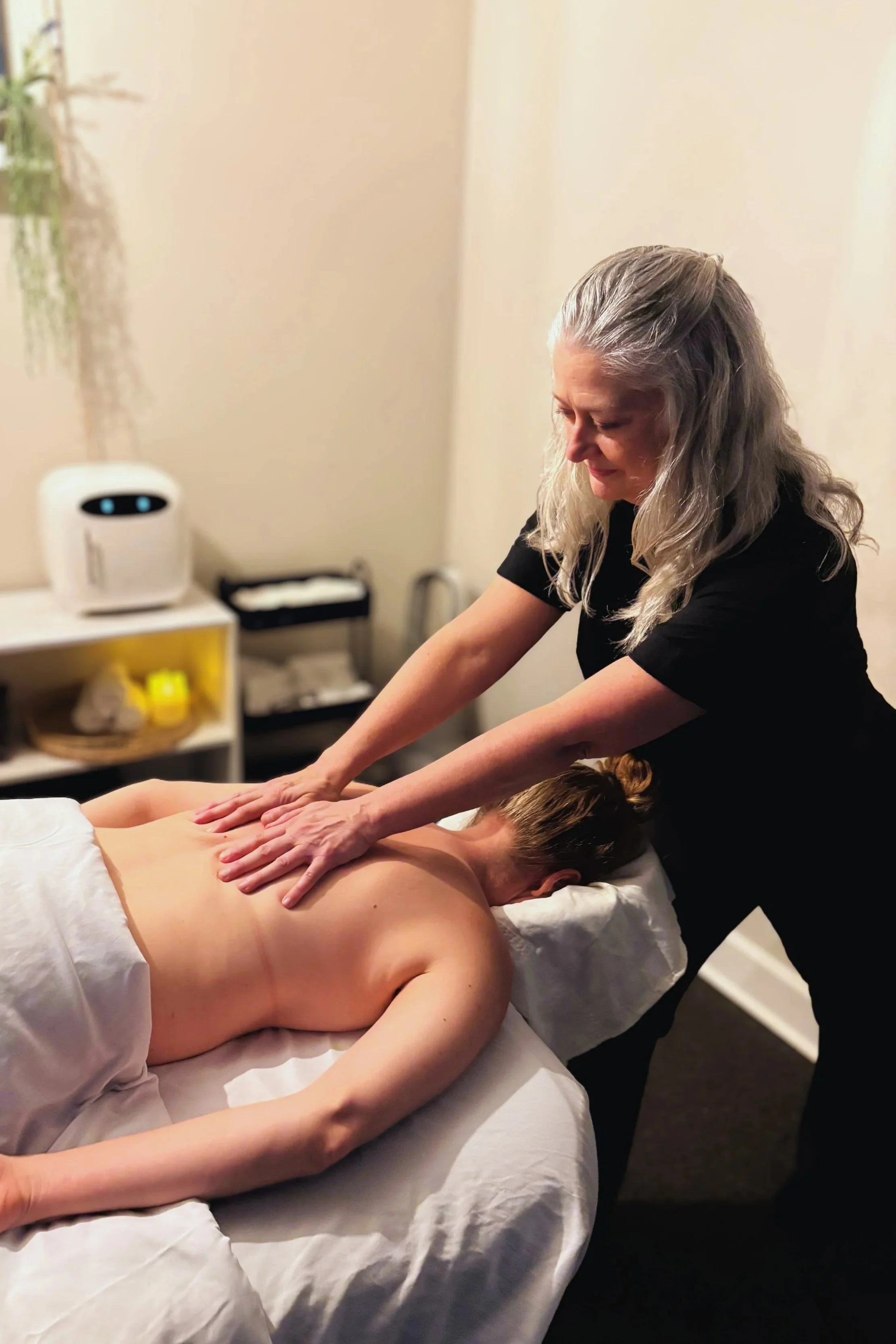 A woman receiving a back massage from a massage therapist in a massage room.
