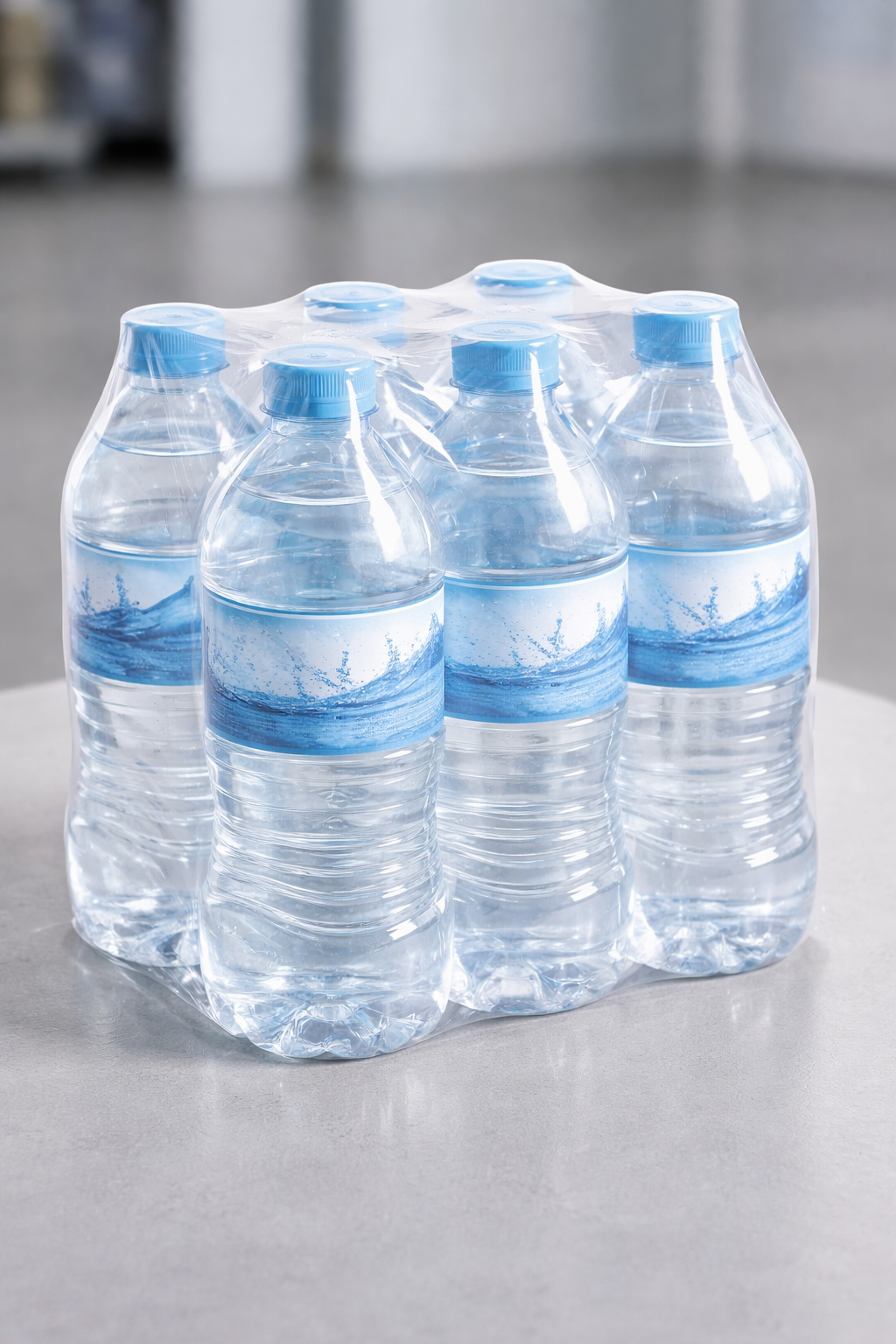Six bottles of water wrapped in plastic on a gray table.