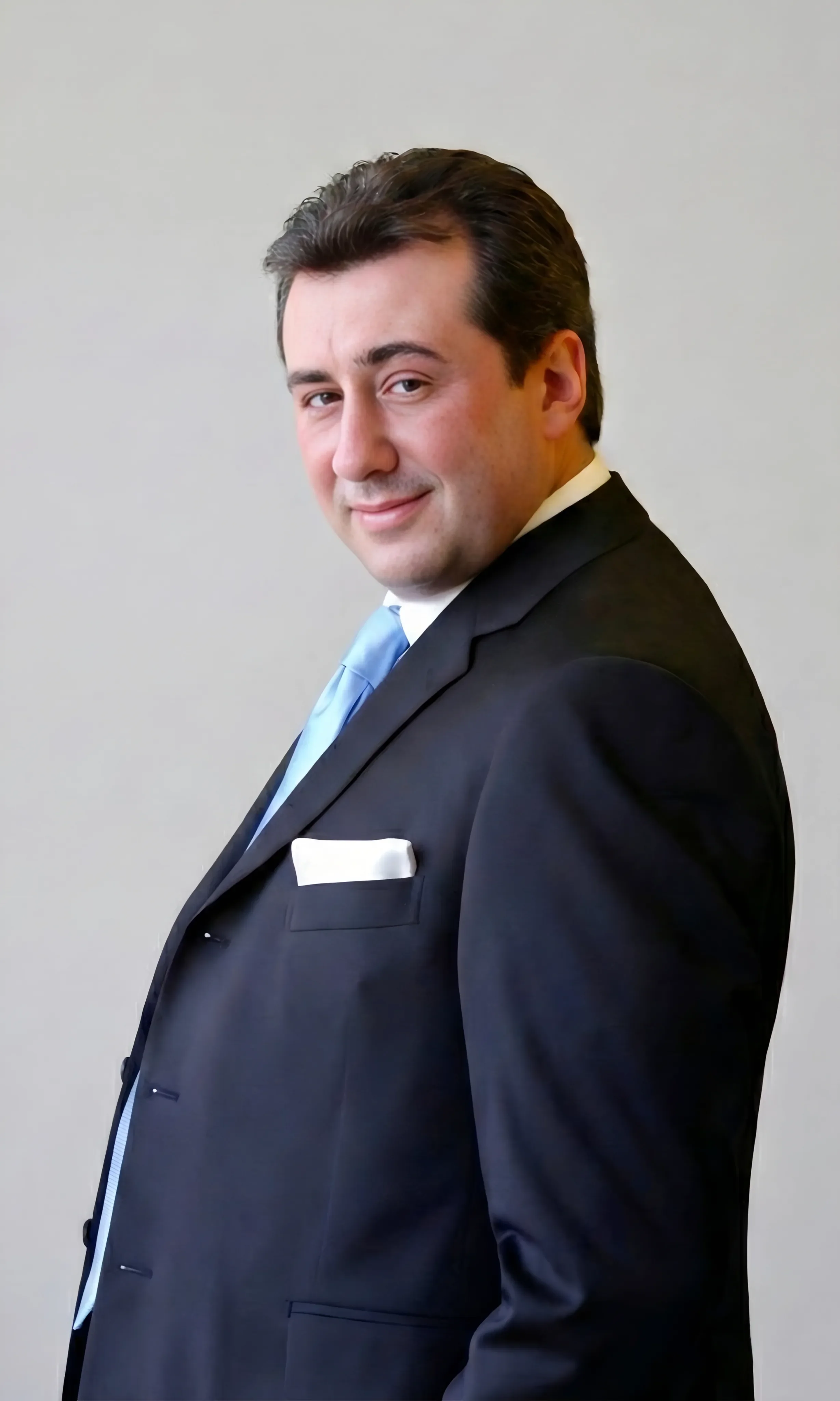 Andrea Stendardo | Senior full-stack engineer | Andrea Stendardo in abito scuro con cravatta azzurra, che sorride e guarda verso la camera.