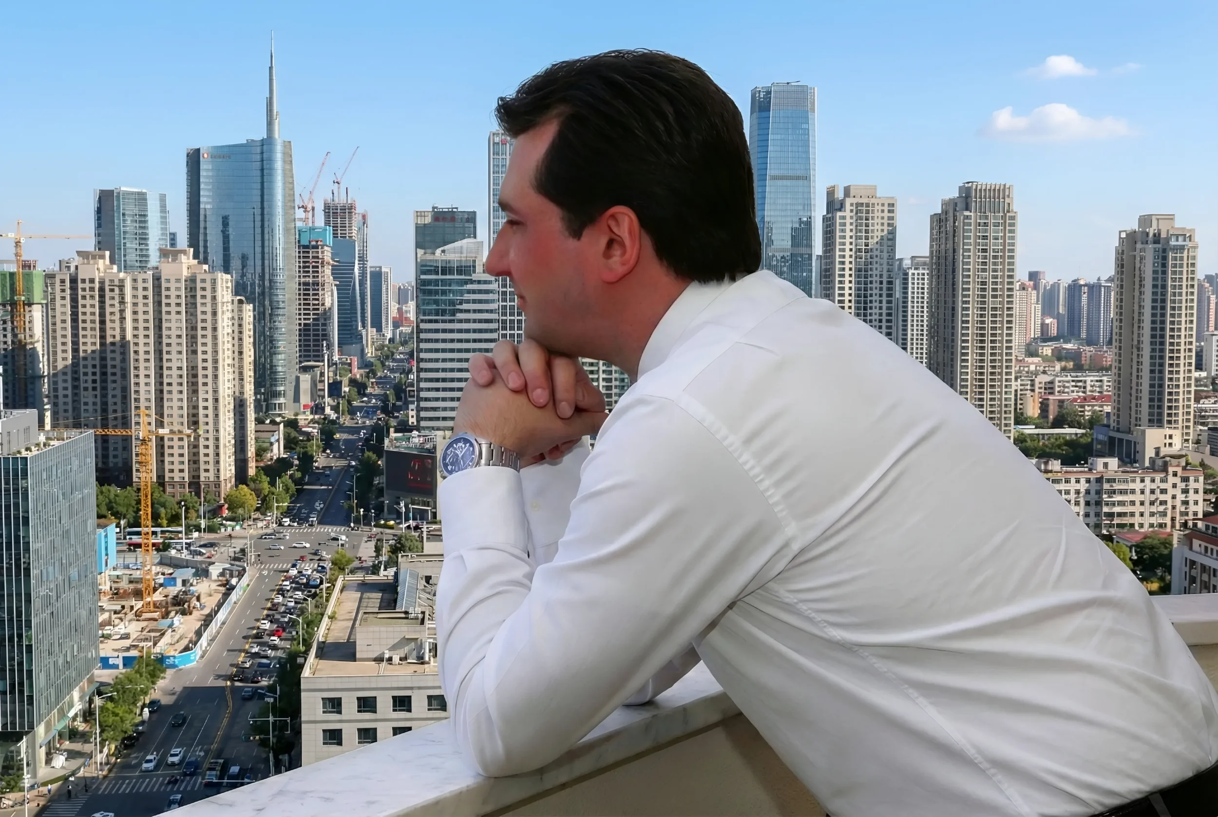 Andrea Stendardo | Senior full-stack engineer | Andrea Stendardo in camicia bianca che guarda la skyline di una città moderna dal balcone.