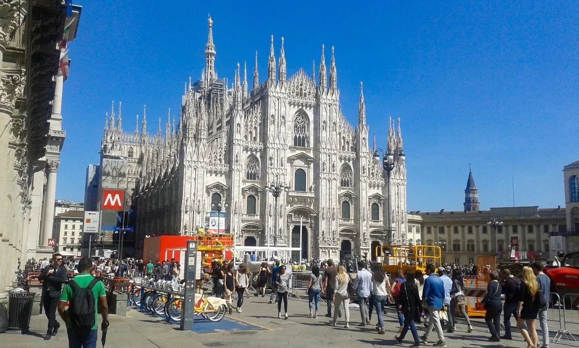 Andrea Stendardo | Senior full-stack engineer | La Piazza del Duomo a Milano con il Duomo di Milano in primo piano e molte persone che camminano. Parte delle biciclette e alcune strutture di cantiere visibili in primo piano.