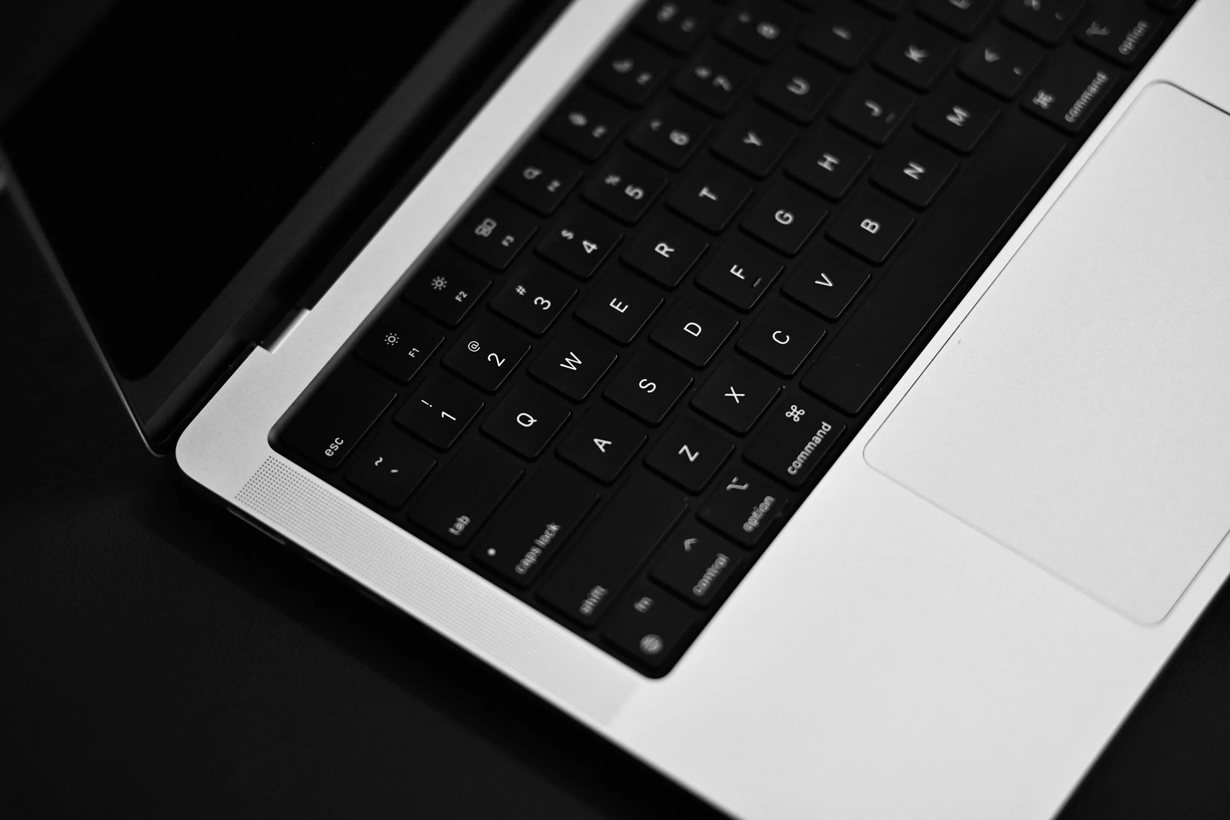 Close-up of a laptop keyboard in black and white, showing keys like 'esc', 'tab', and 'command'.