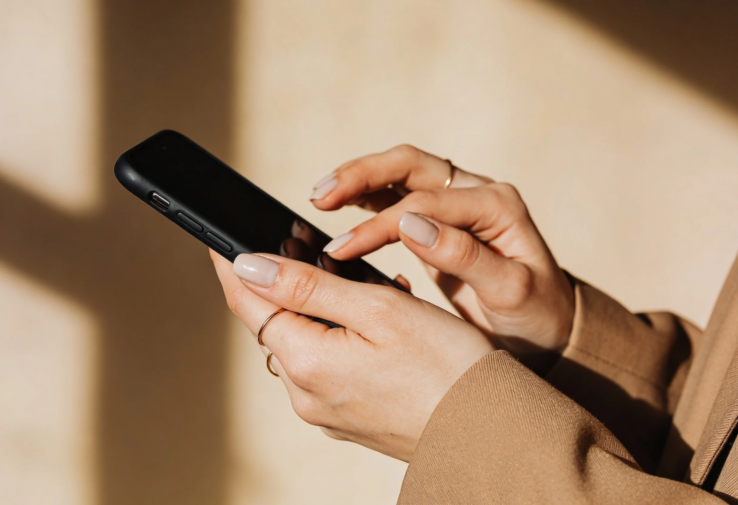 Close-up of a woman's hands holding and using a black smartphone.