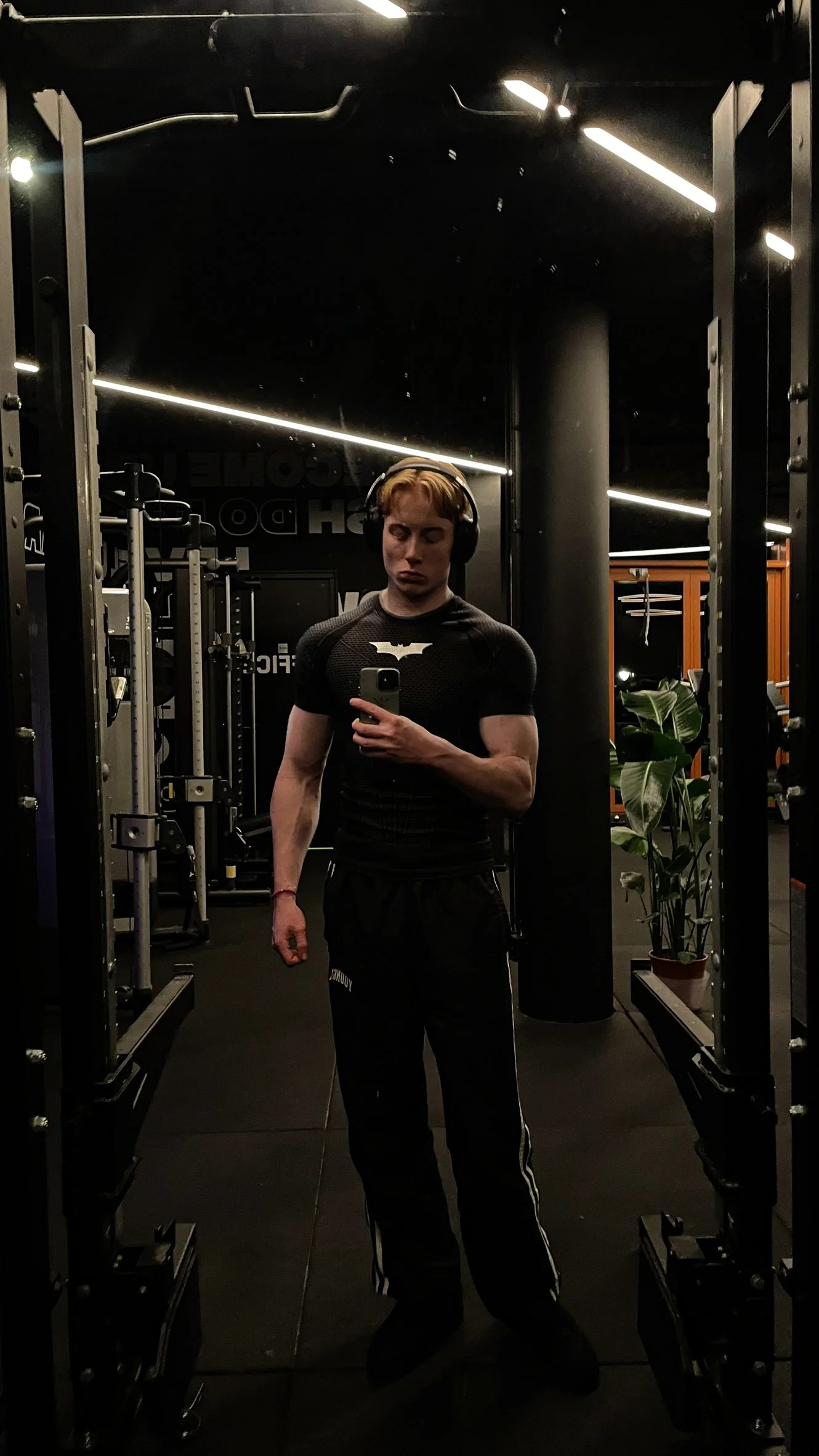Jelle de Kruijff taking a mirror selfie in a dimly lit gym, wearing headphones