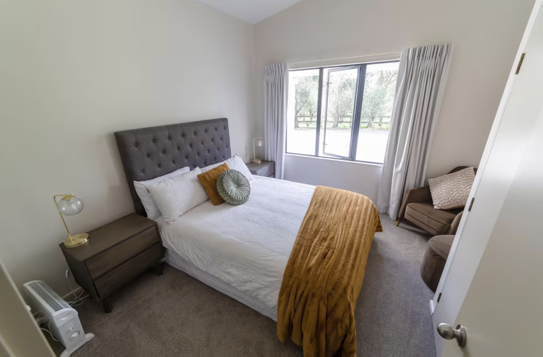 Bedroom with a bed, nightstands, a window, and a small chair.