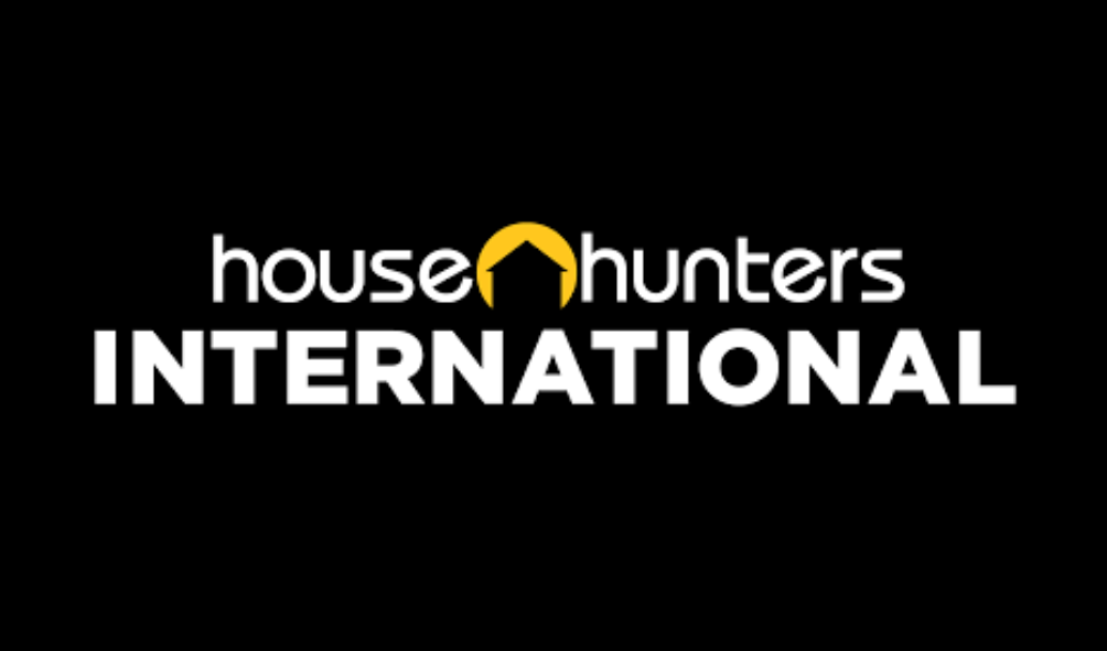 Logo for House Hunters International with a black background, white text, and a yellow house-shaped arrow integrated into the text.