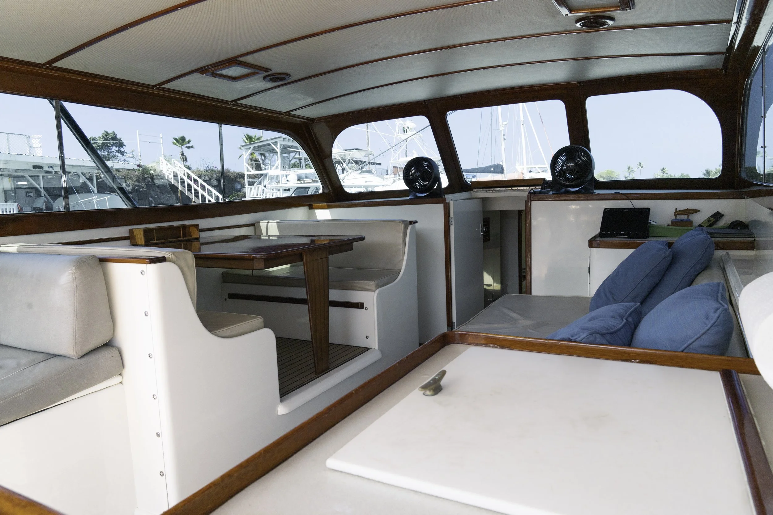 Interior of the yacht with seating area, a table, and large windows.