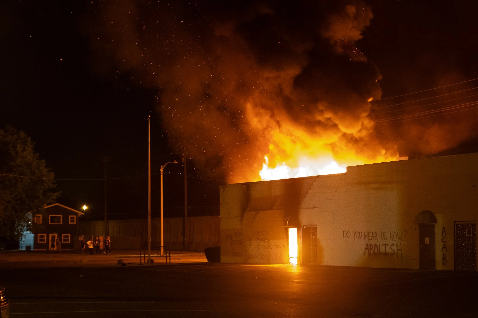 The Dept. of Corrections on fire. Again, like in a movie I stand and watch this unfold. I take a photograph. Spray paint reads Rusten Sheskey you did this. An arrow points to the fire. Sheskey was the cop that shot Jacob Blake in the back. Shouts of 