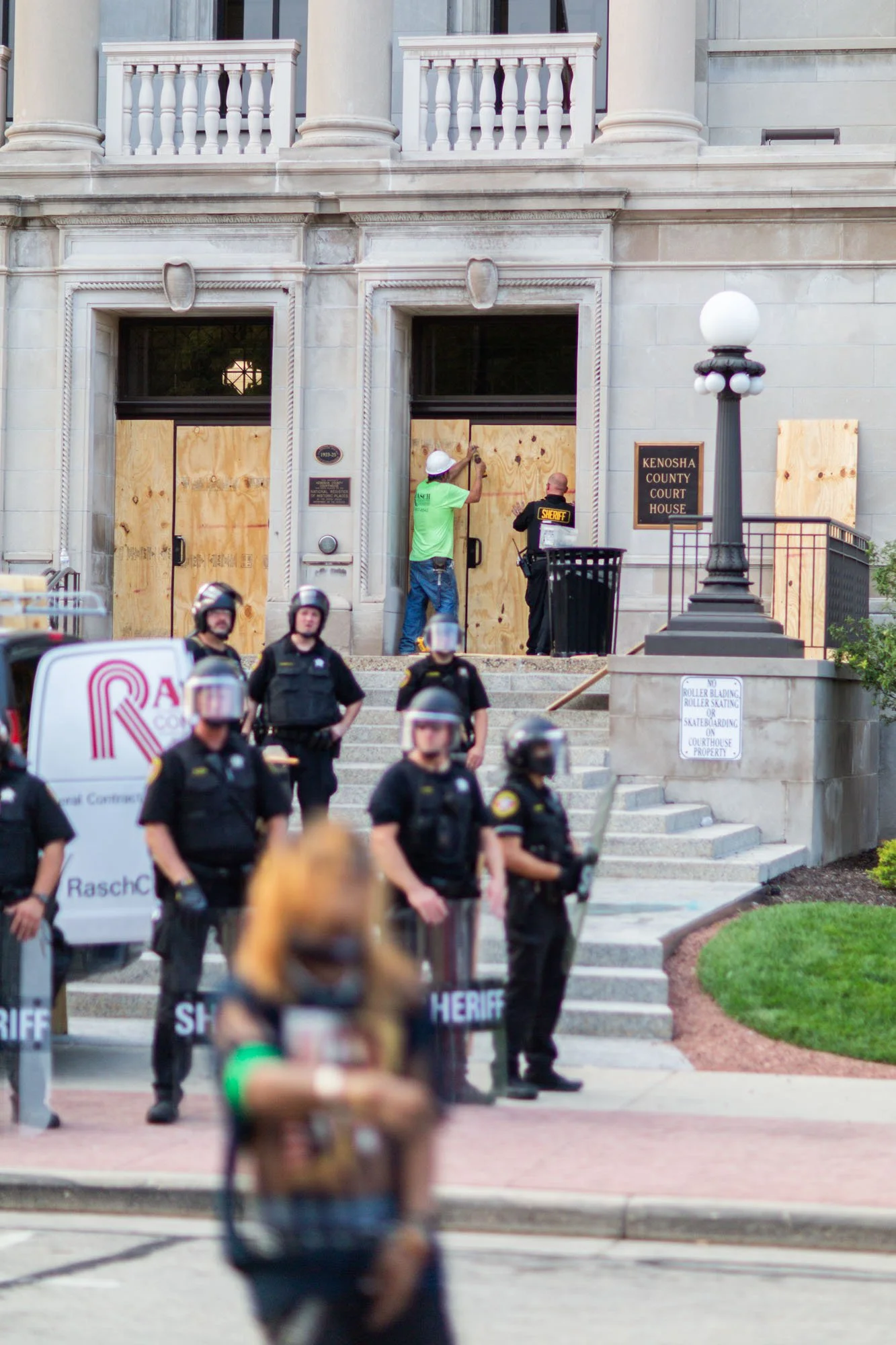 Three levels of a photograph. Three jobs. Securing the Kenosha County Court House. The sheriffs department unpacking. And blurred in the foreground, a music video in production, an Asian holding his or her crotch and rapping. That situation caught my