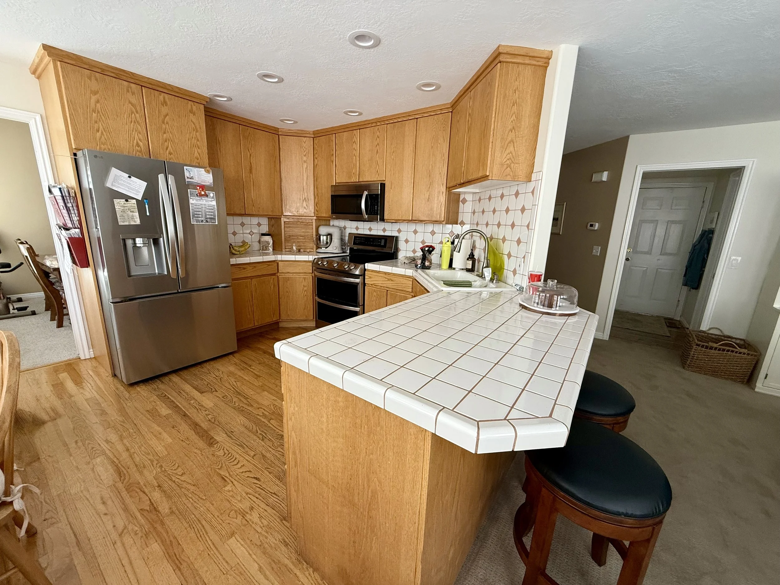 BEFORE | Cottonwood Heights, Utah: This kitchen featured traditional oak cabinetry, white tile countertops, and a dated patterned tile backsplash. While the existing cabinets were in good condition, the homeowner wanted a brighter, more modern kitche