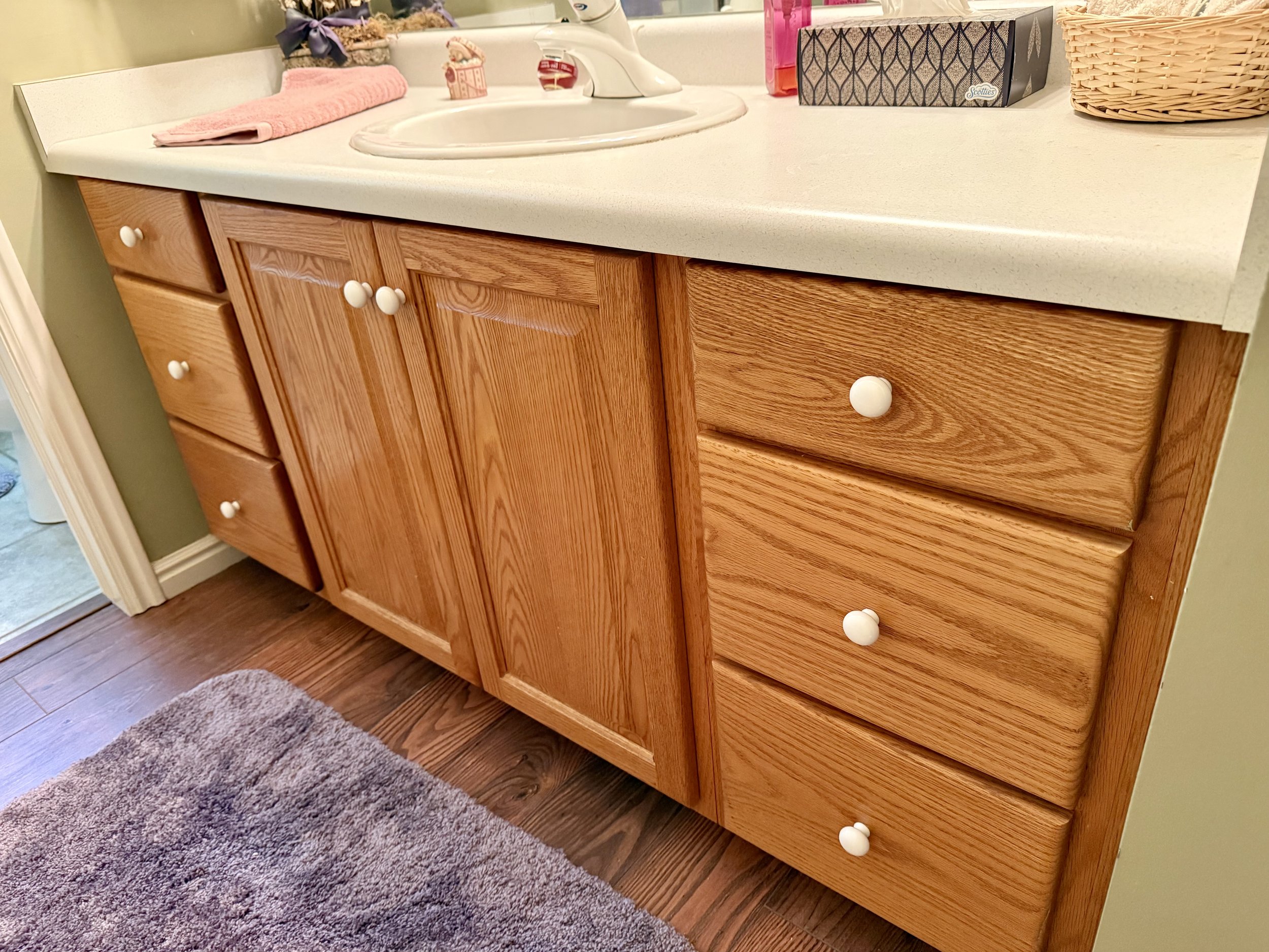 Original orange-toned wood bathroom vanity in North Salt Lake before cabinet restaining