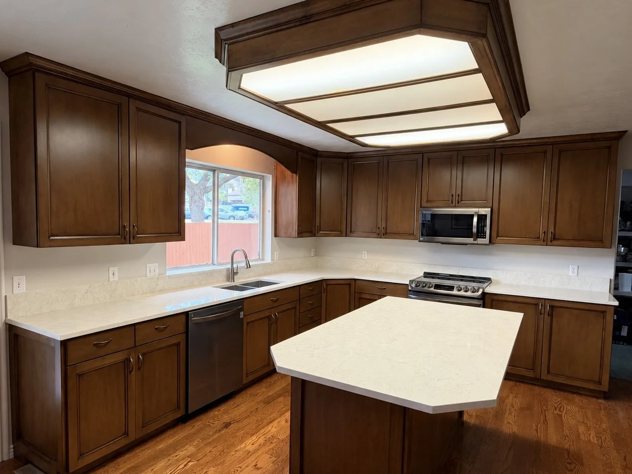 AFTER | Cabinet refinishing in Cottonwood Heights with new Shaker doors, custom trim on the island and perimeter end panels, and new quartz countertops replacing the original tile.