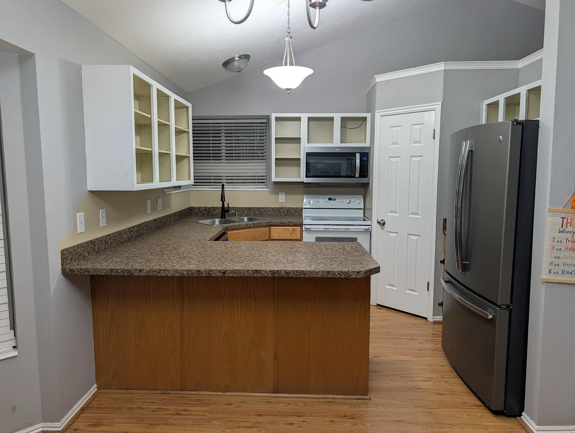 Layton, Utah kitchen before cabinet refacing by CAZI Refined Finishes, showing existing cabinet doors and drawer fronts before installation of new Shaker-style doors, flat drawer fronts, and decorative peninsula trim.