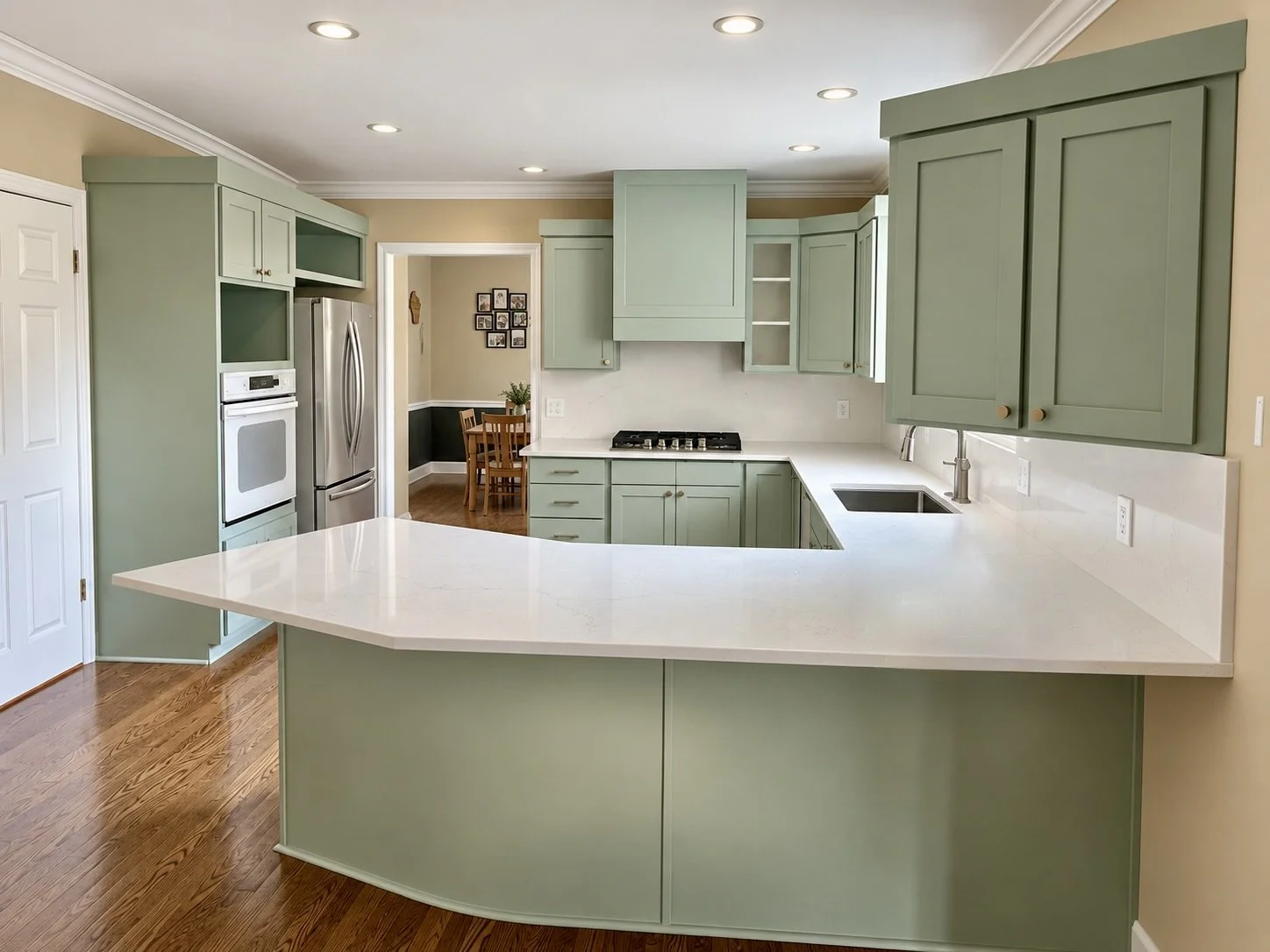 Sandy, Utah kitchen after cabinet refinishing with new shaker doors, custom vent hood, crown molding and quartz countertops with full height backsplash