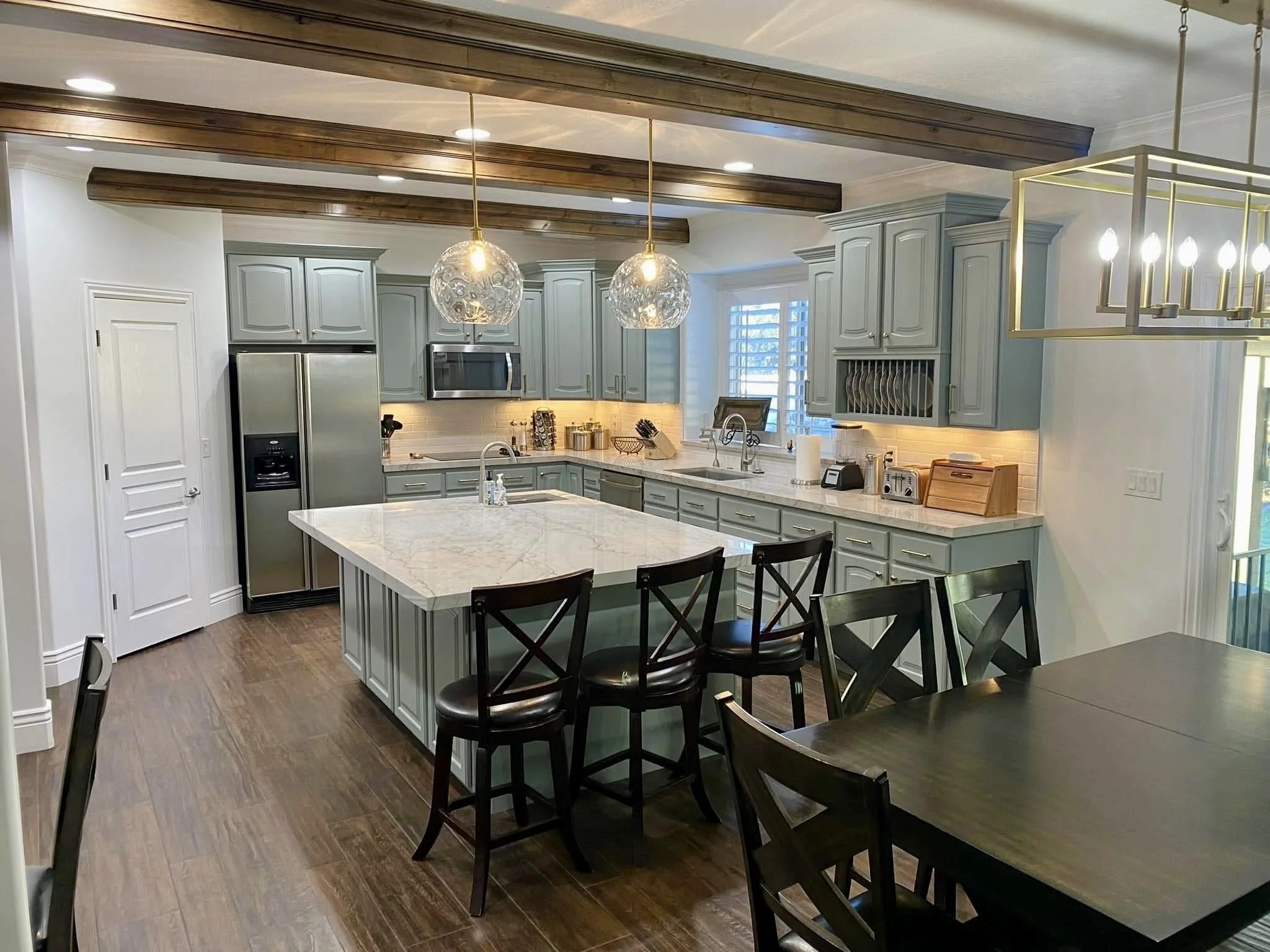 Kitchen cabinet refinishing with painted cabinetry, quartz countertop upgrade, and dark stained wood ceiling beams