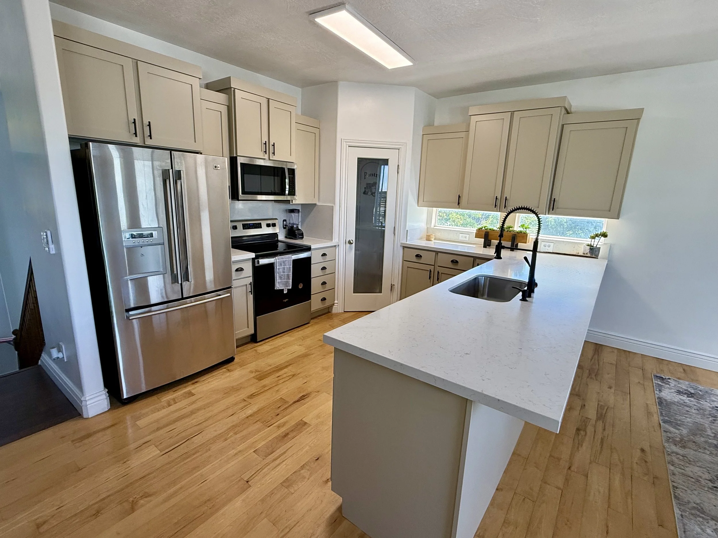 North Salt Lake, Utah kitchen after cabinet refinishing with Windsor Greige Shaker cabinets and quartz countertops