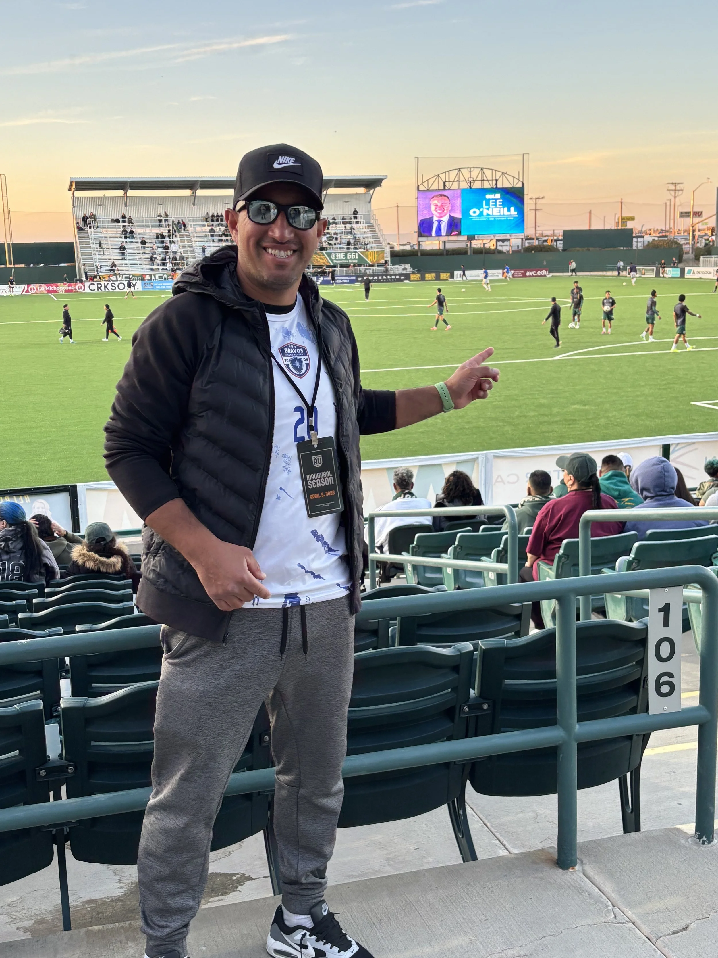 Gerardo Bravo smiling and pointing at a soccer field in Lancaster watching AVFC play there first ever game