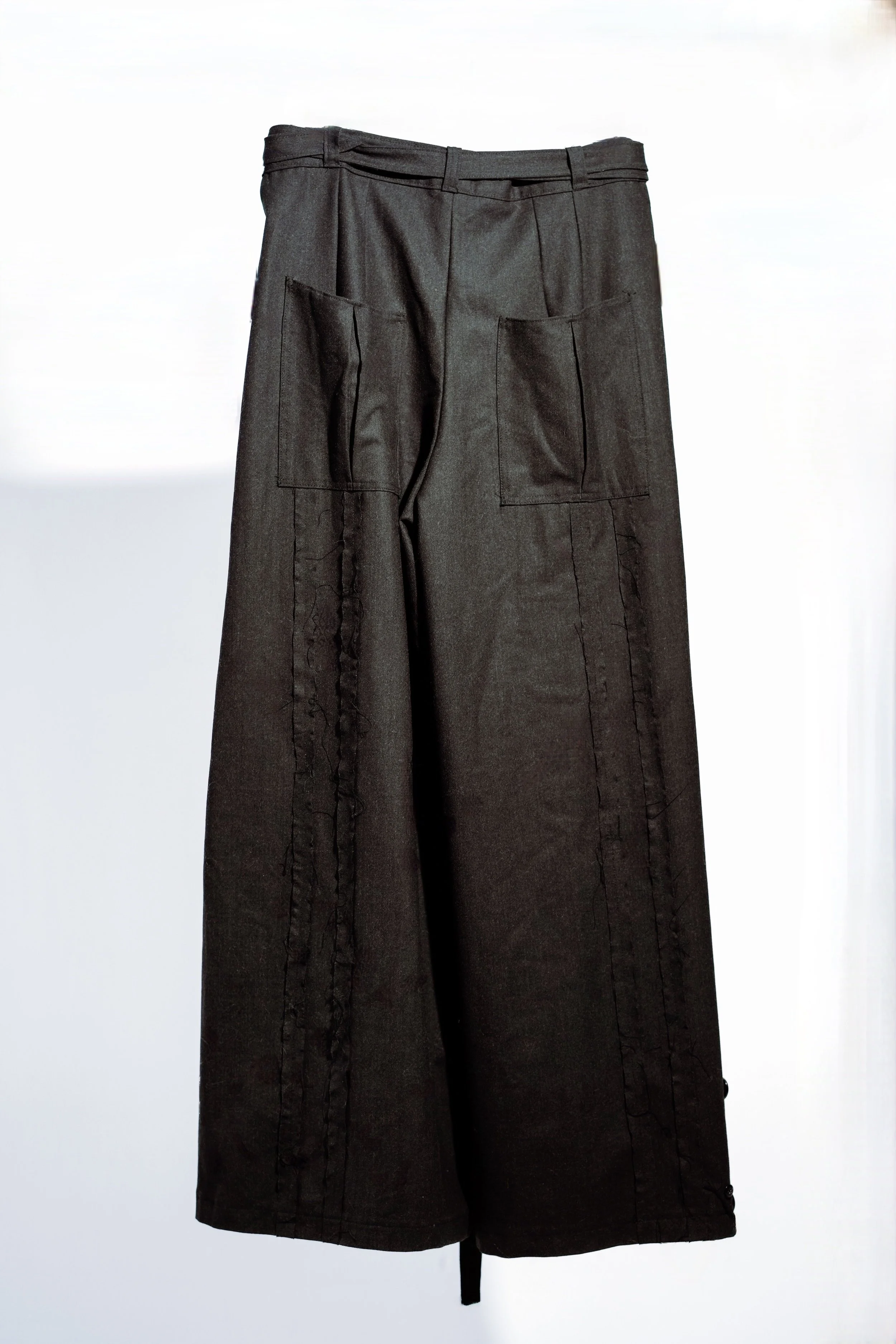 Black wide-leg pants with front pockets hanging against a white background.