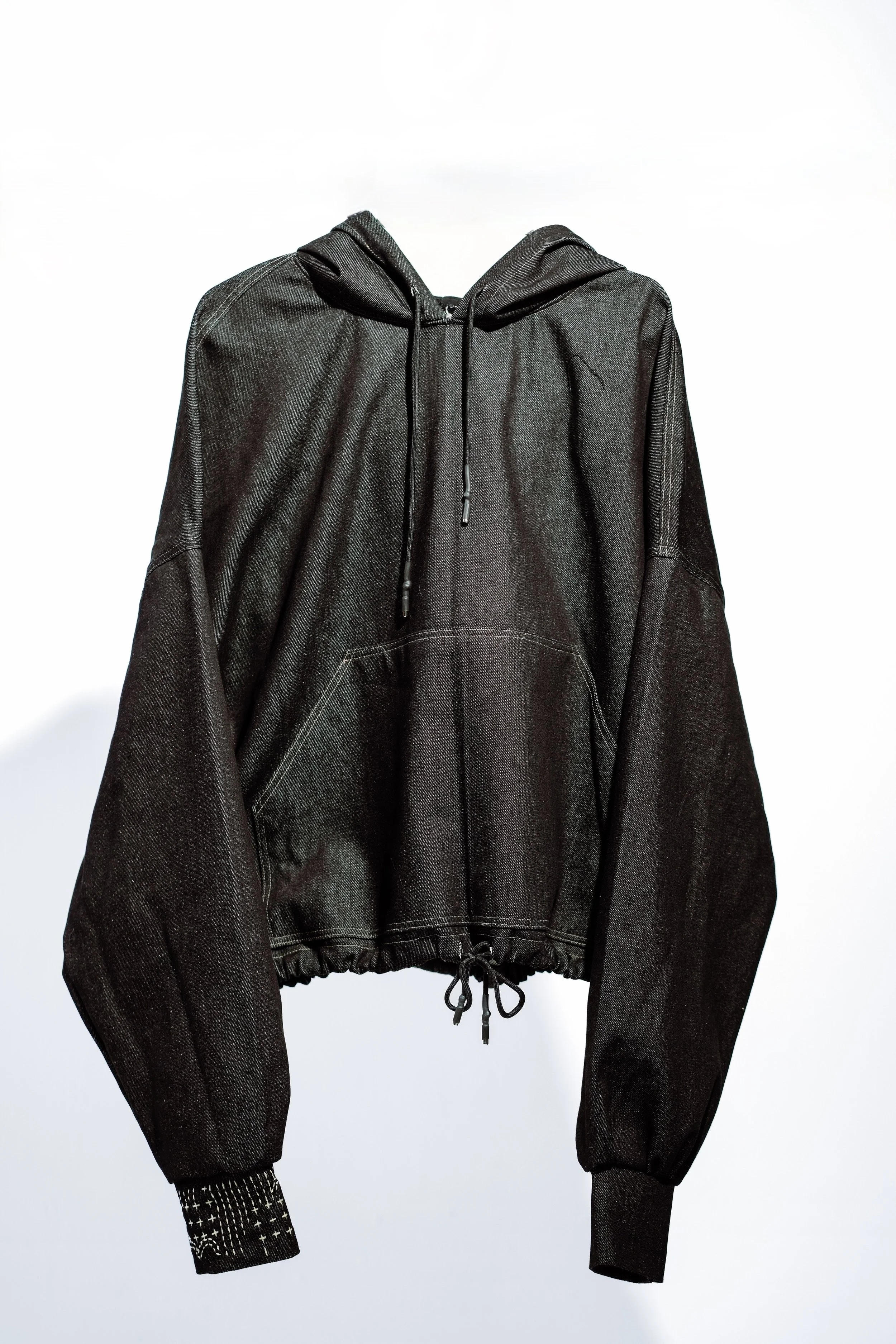 Black hoodie with drawstrings and ribbed cuffs, displayed on a white background.