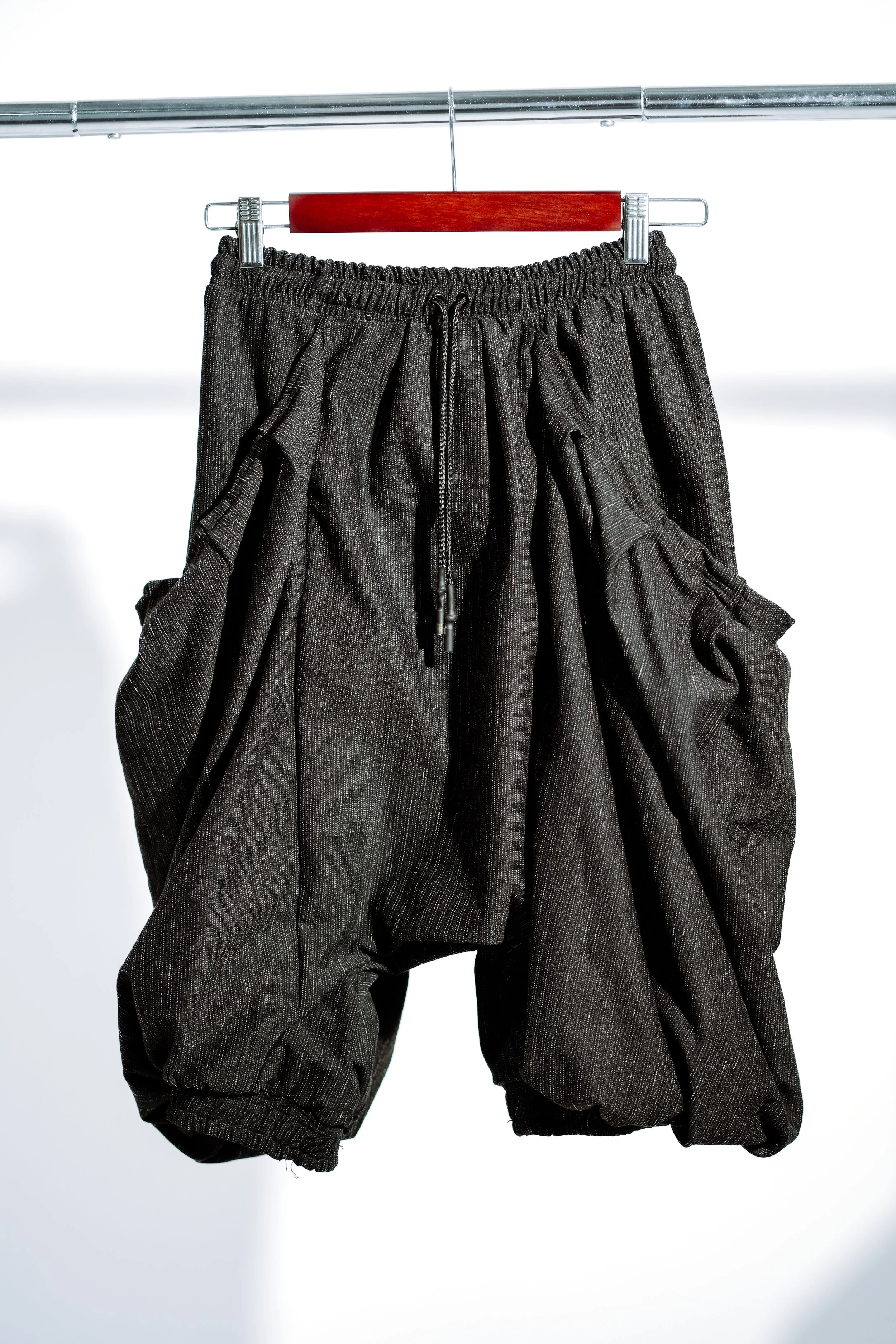 Black baggy shorts hanging on a clothing rack.