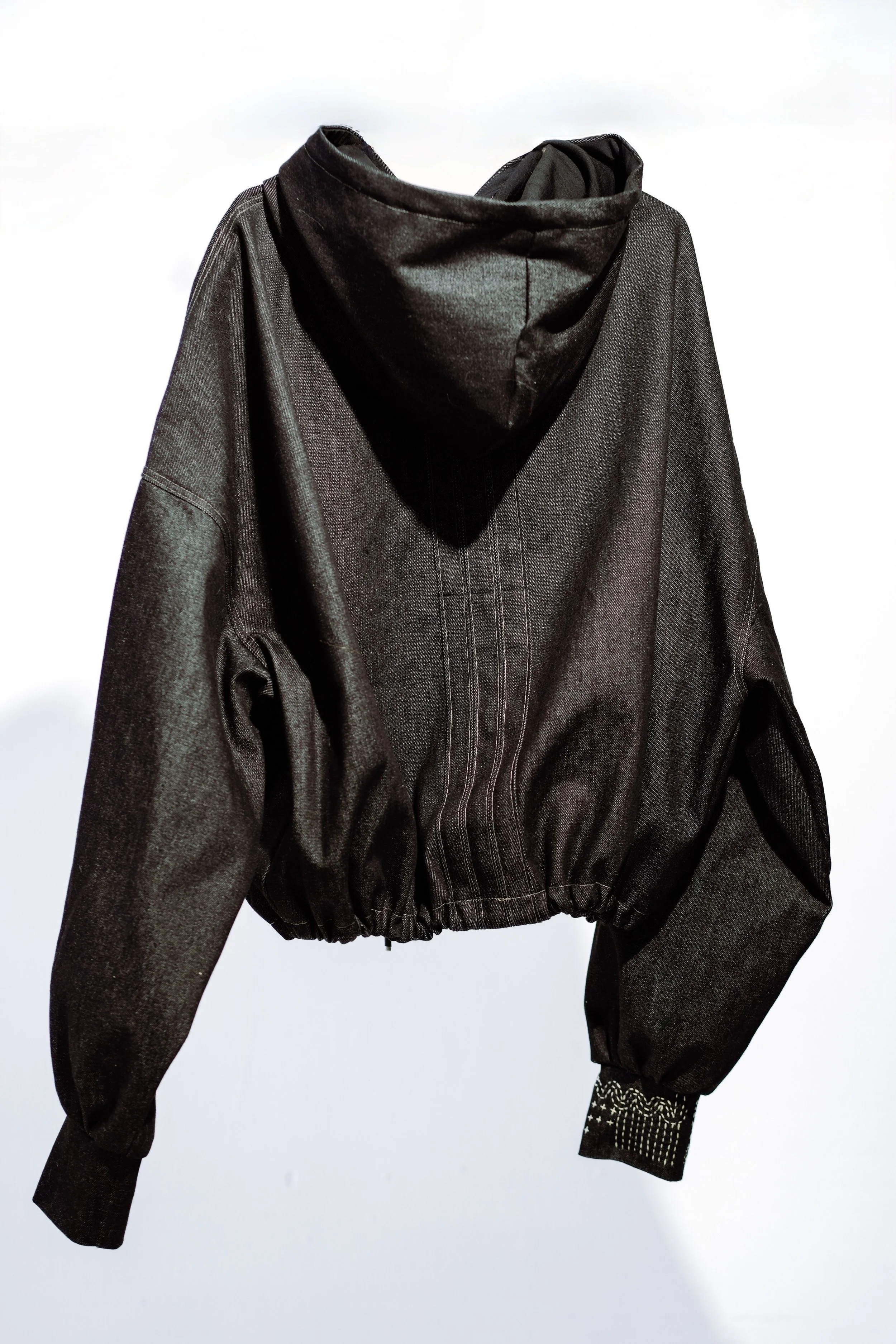 Black hoodie jacket hanging against a plain light background.