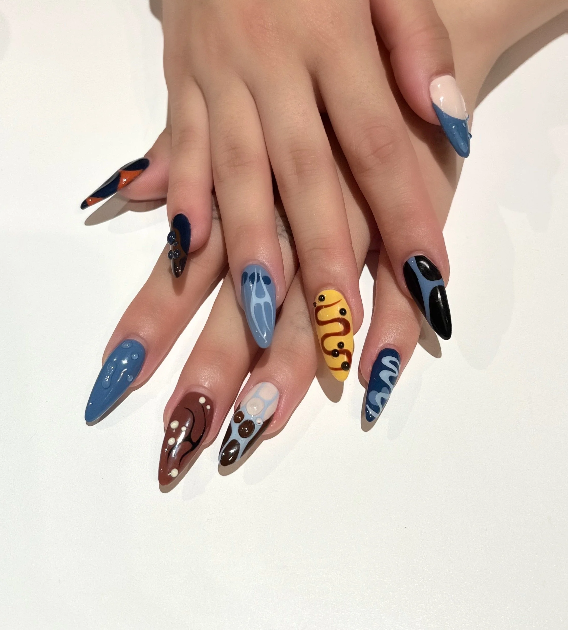 Hands with colorful, artistic painted nails resting on a white surface.