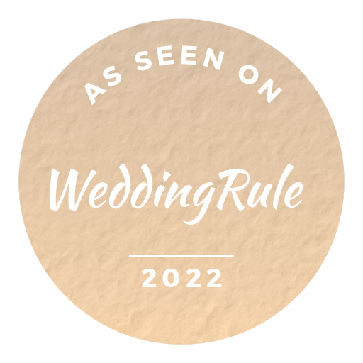 A beige circular badge with white text that reads "As Seen On WeddingRule 2022."