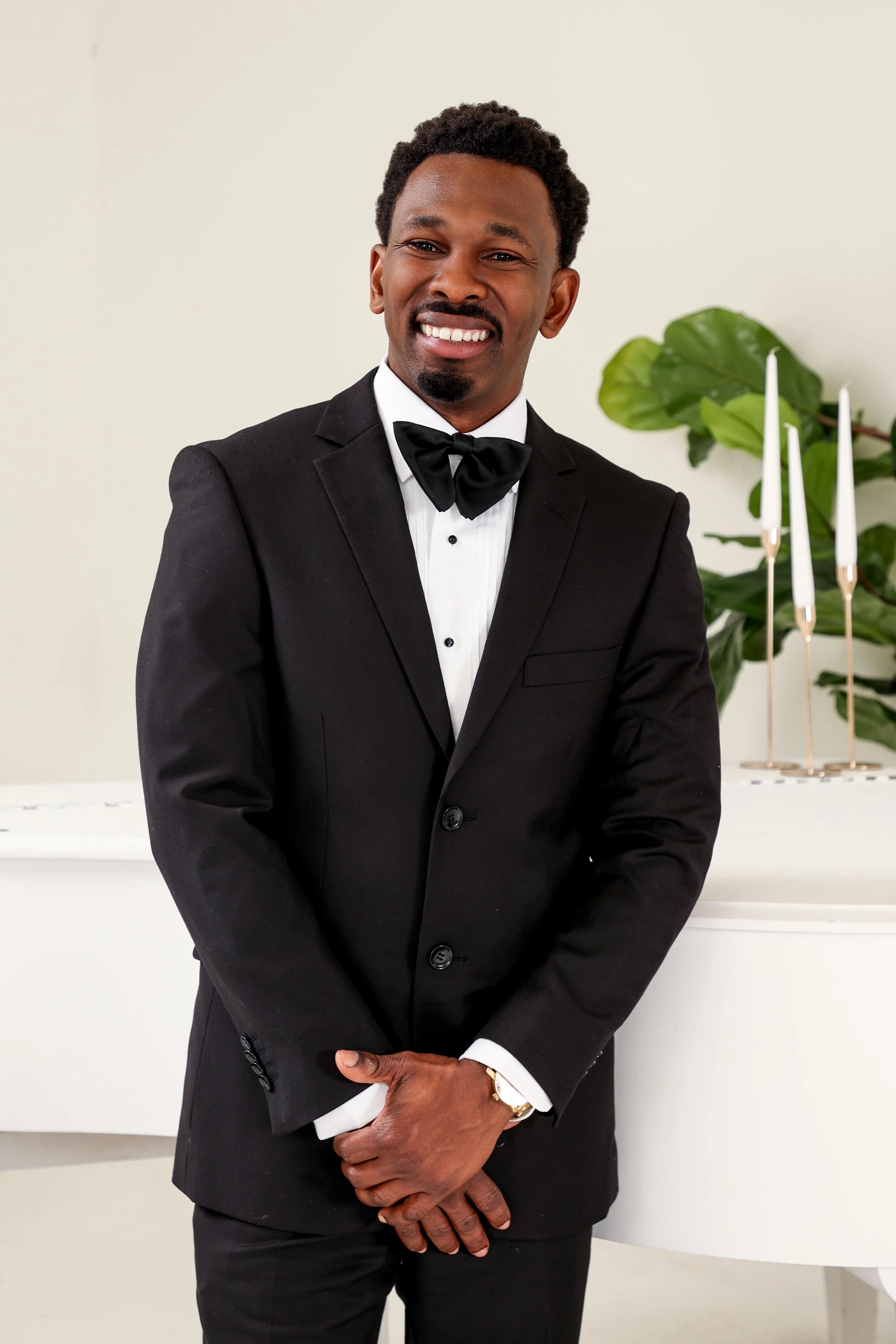 Two floral arrangements with pink, purple, and white flowers on a white tablecloth in front of a wallpaper with a landscape scene of trees and buildings.