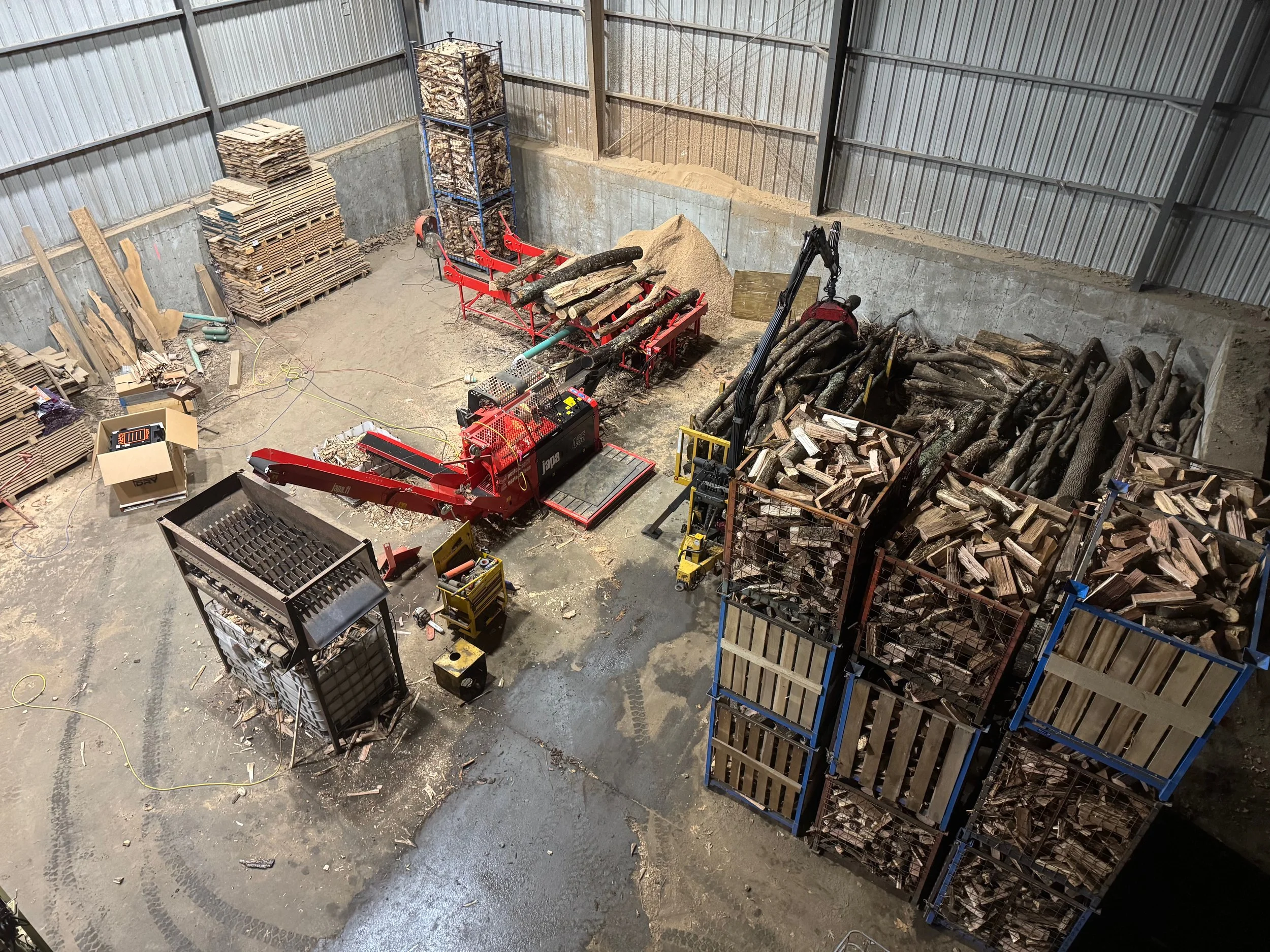 A storage area with firewood, logs, and a wood processing machine.
