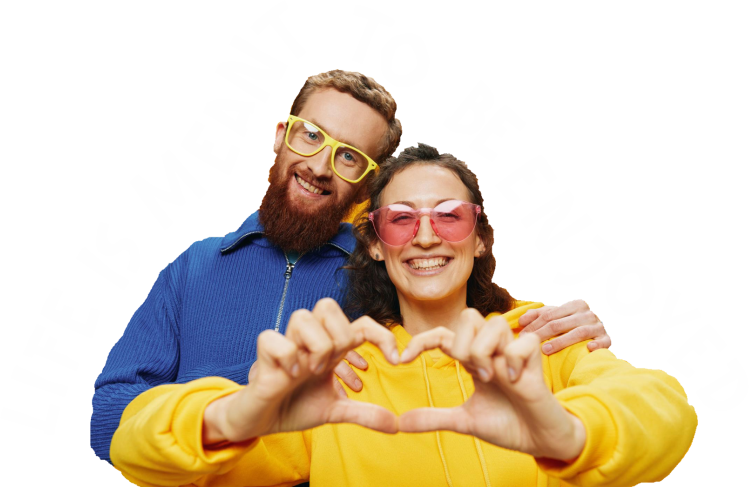 A smiling man and woman wearing colorful sunglasses and yellow clothing, forming a heart shape with their hands.