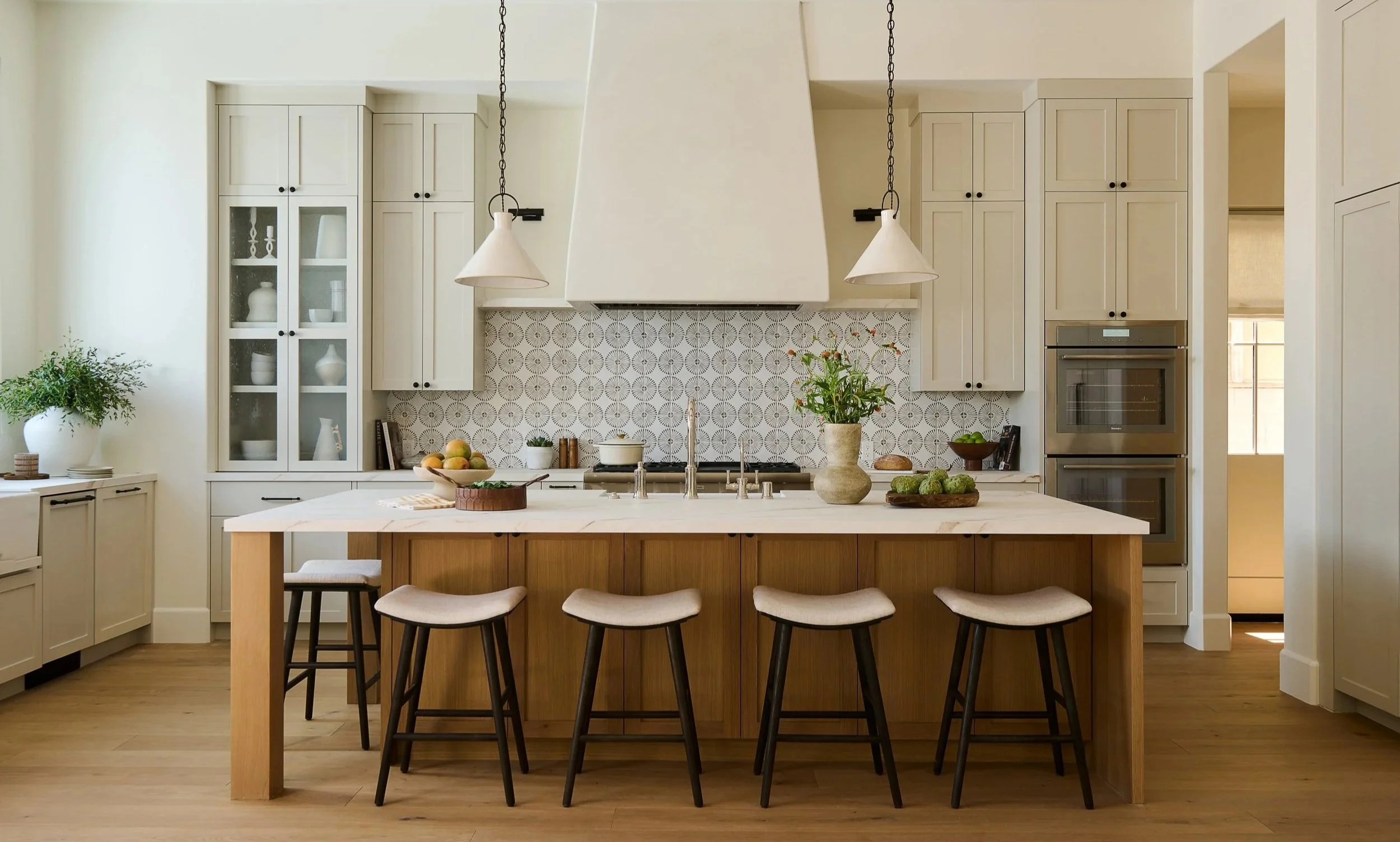 Modern kitchen with white cabinets and a wooden marble island, featuring four bar stools. South Redondo project in Los Angeles.
