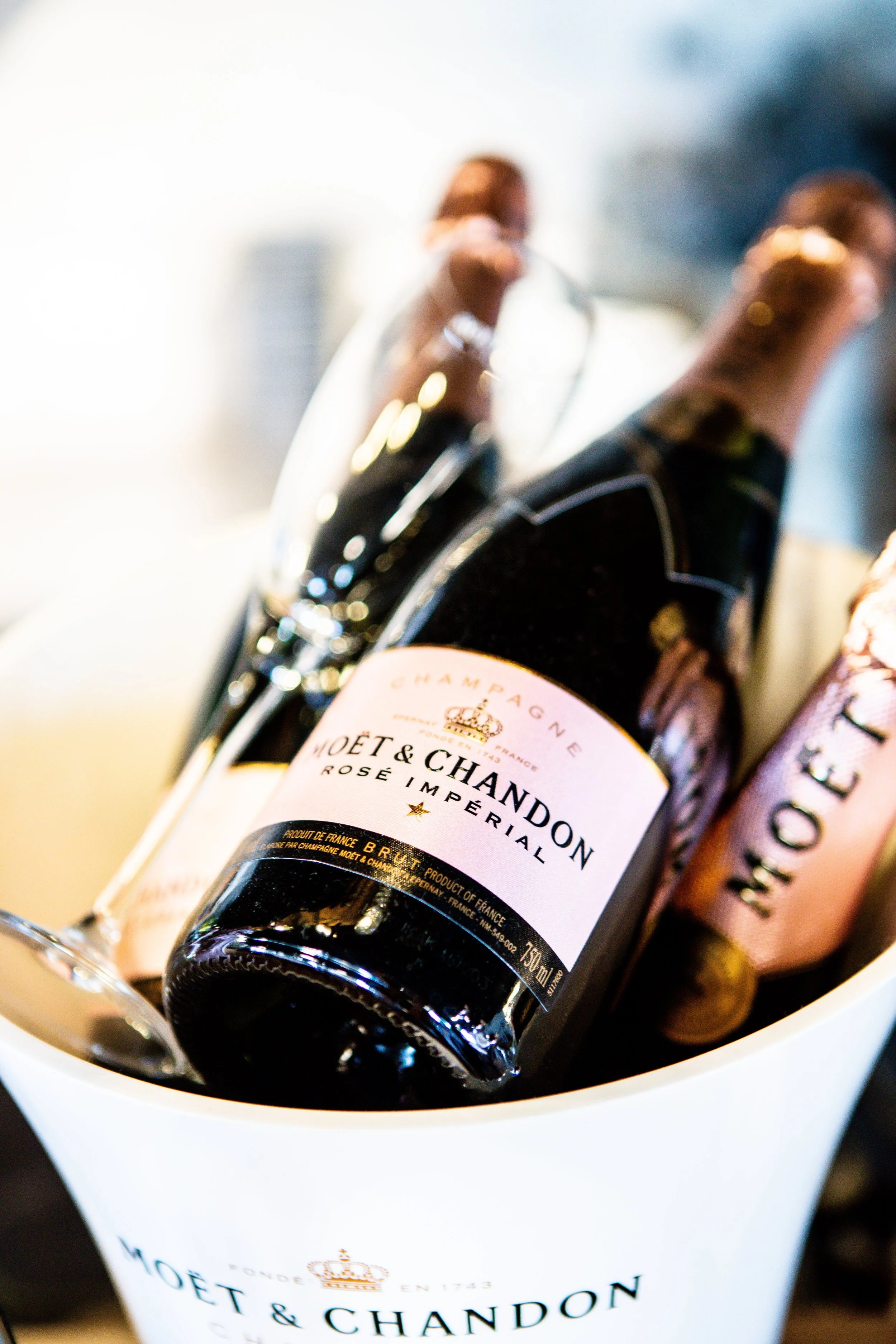Three bottles of Moët & Chandon champagne in a white ice bucket.